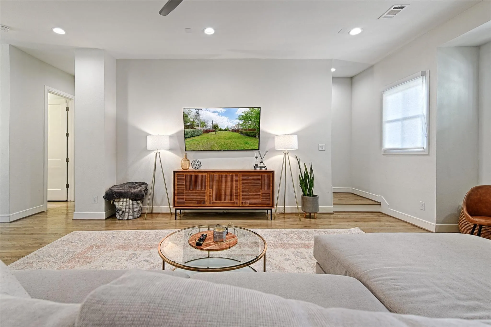 Recessed lighting, wood-finish flooring, white trim, and a window with a roller shade