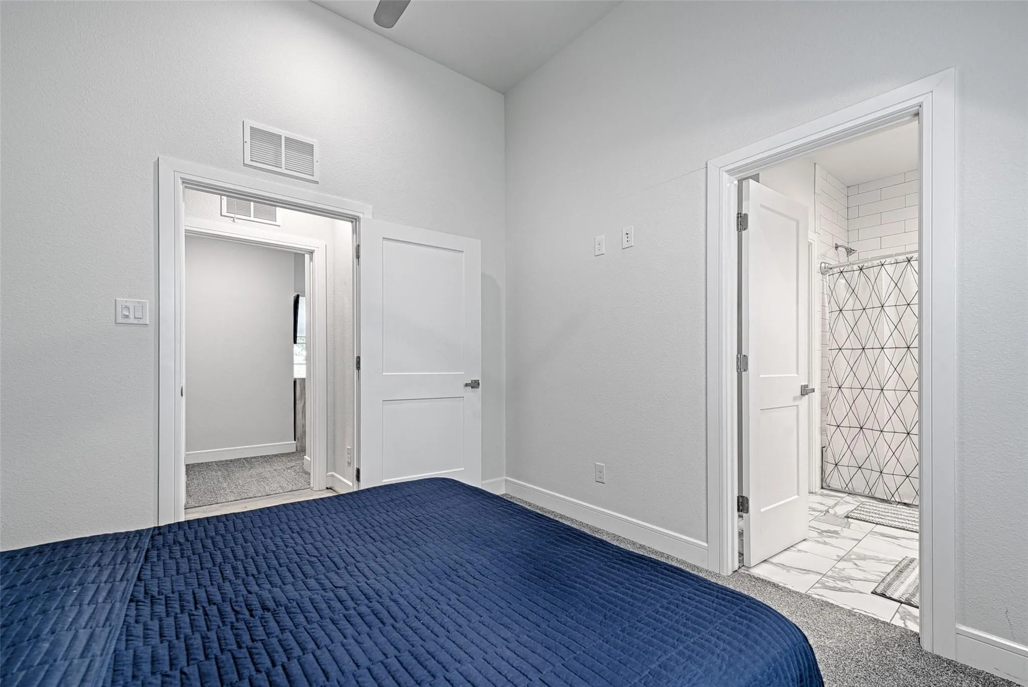 Vaulted ceiling, clean white walls, carpeted flooring, and a white subway tile shower