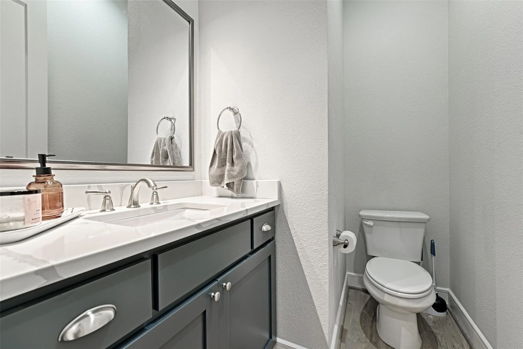 Vanity with an integrated sink, quartz countertop, framed mirror, and brushed nickel fixtures