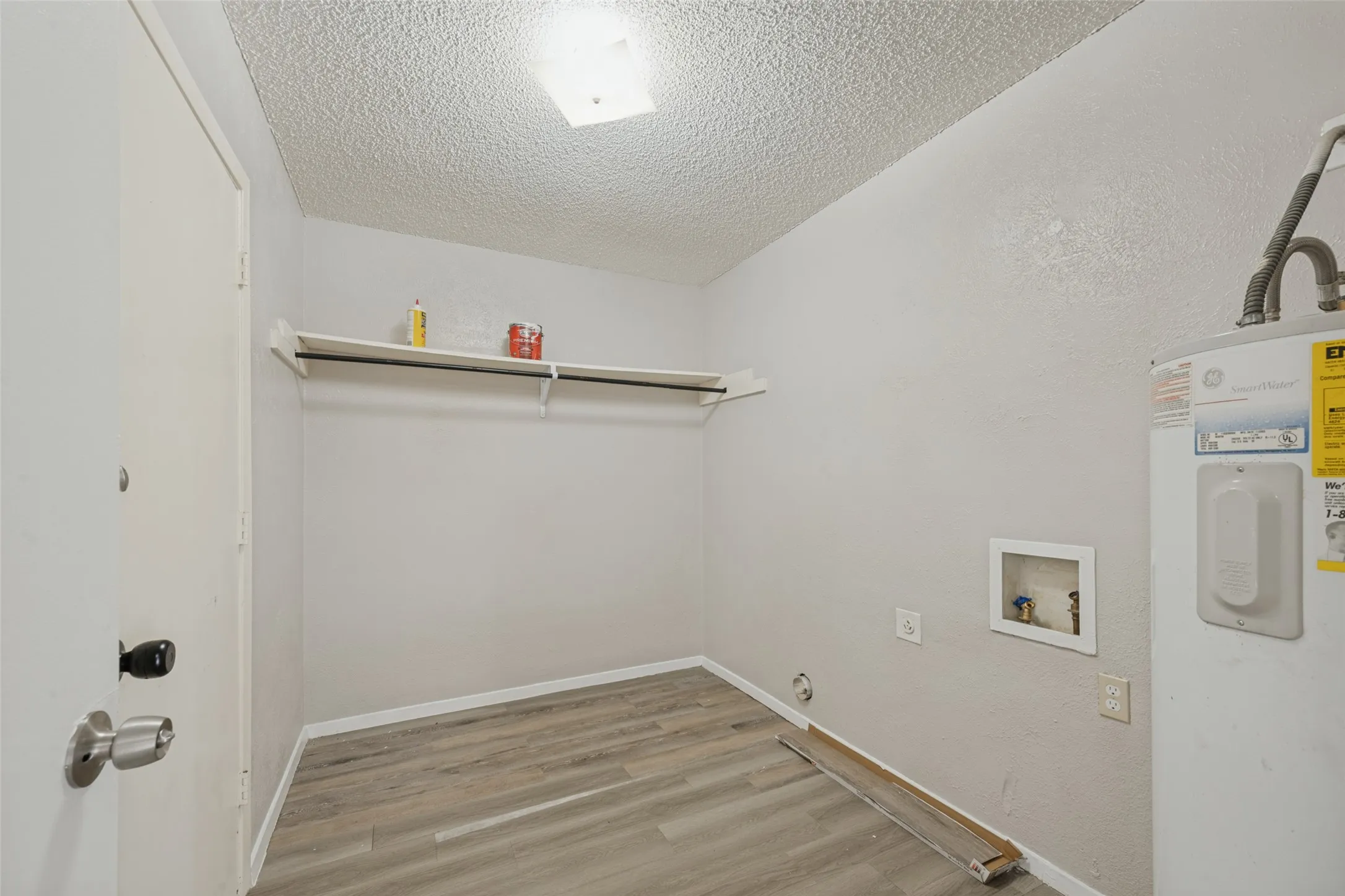 Utility area with wood-finish flooring, built-in shelving, and a water heater