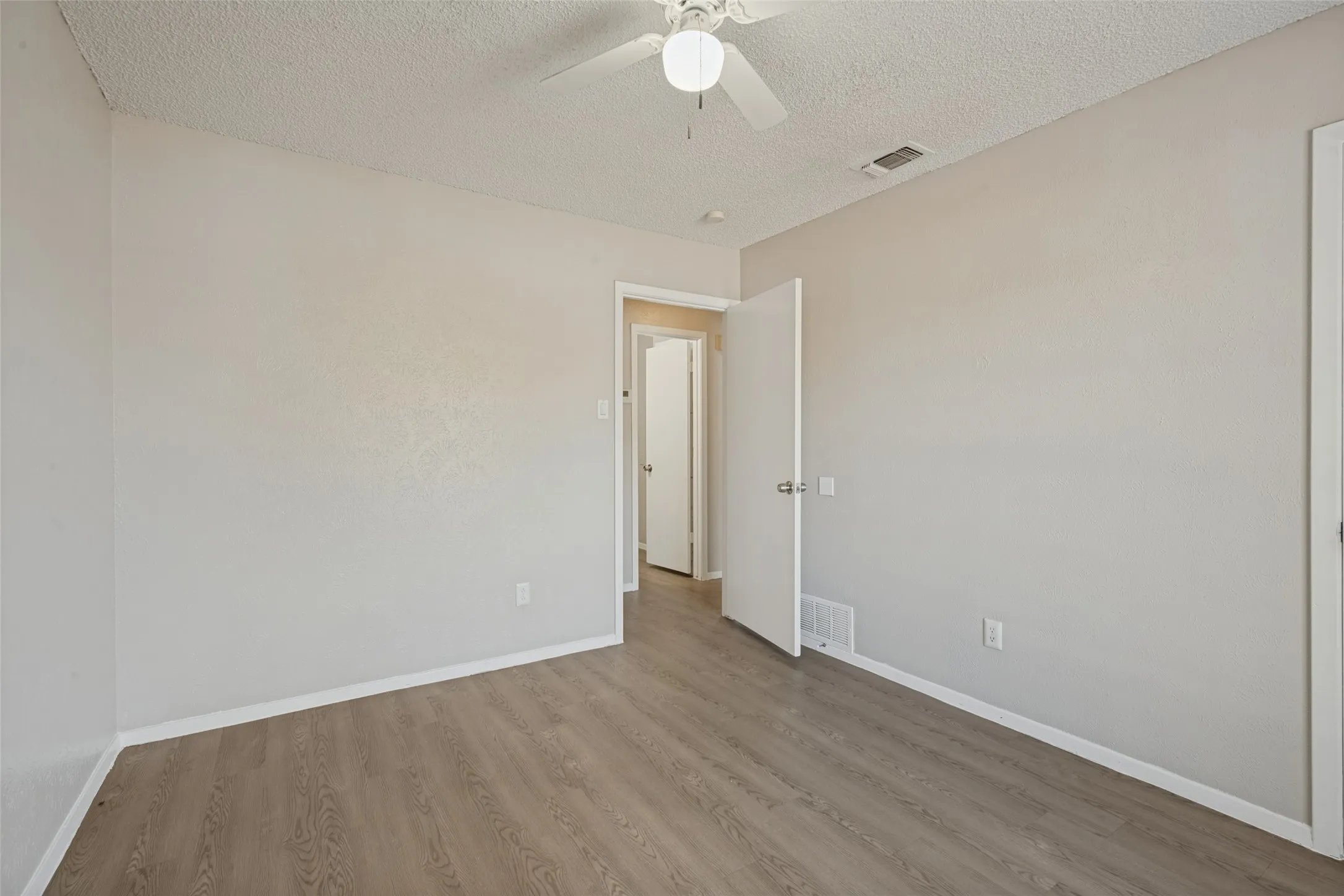 Wood-finish flooring with white trim and a neutral wall color