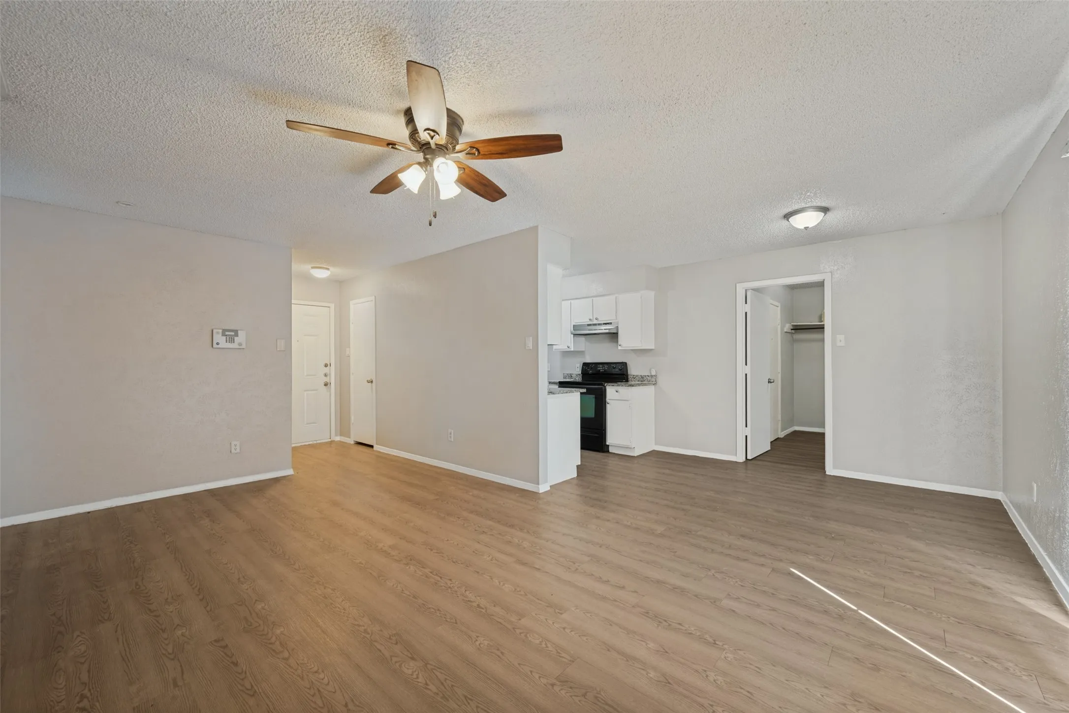 Spacious living area featuring wood-finish flooring, a ceiling fan, and recessed lighting