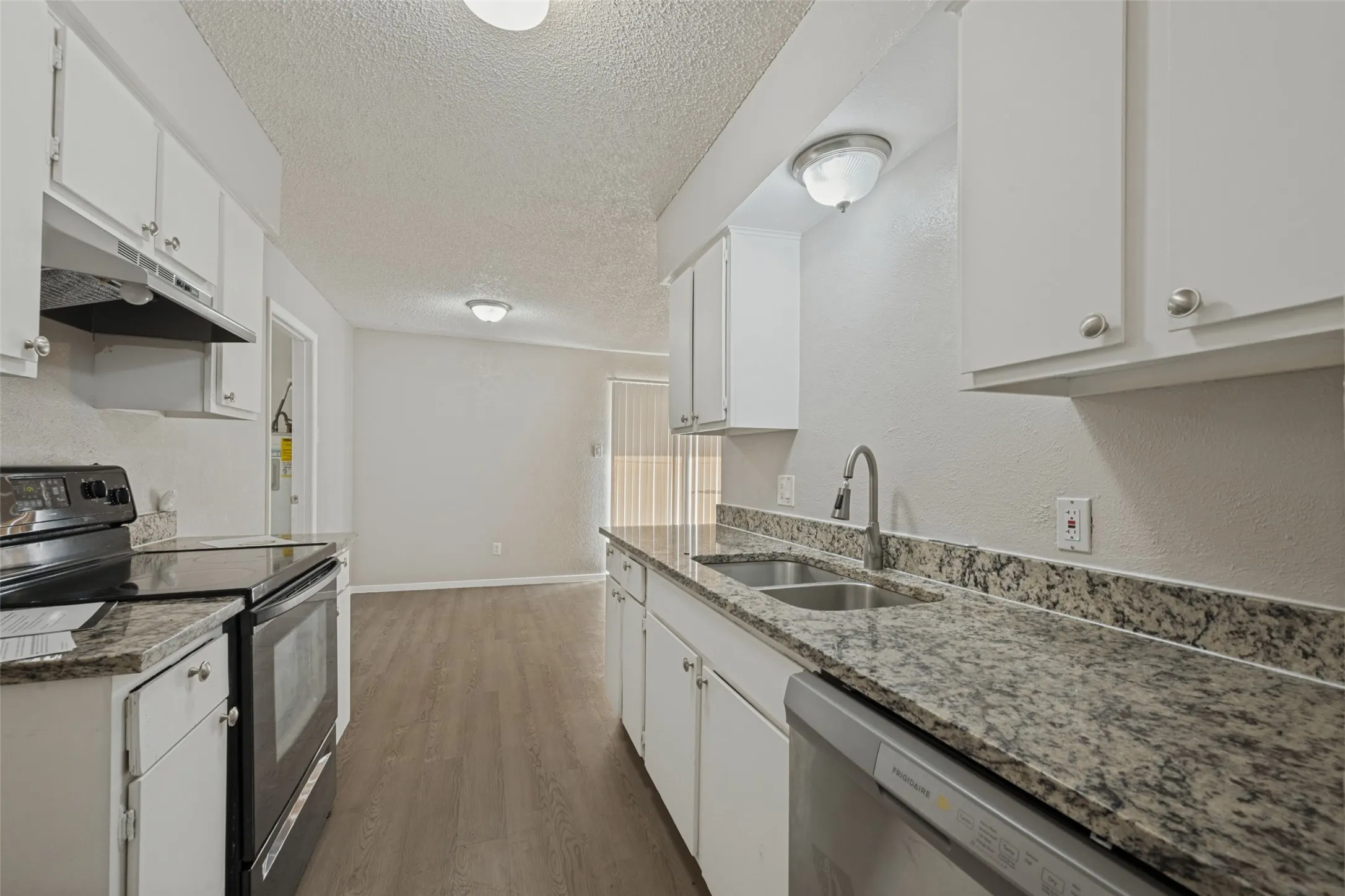 Kitchen featuring white cabinetry, speckled countertops, stainless steel sink, black electric range, and wood-finish flooring