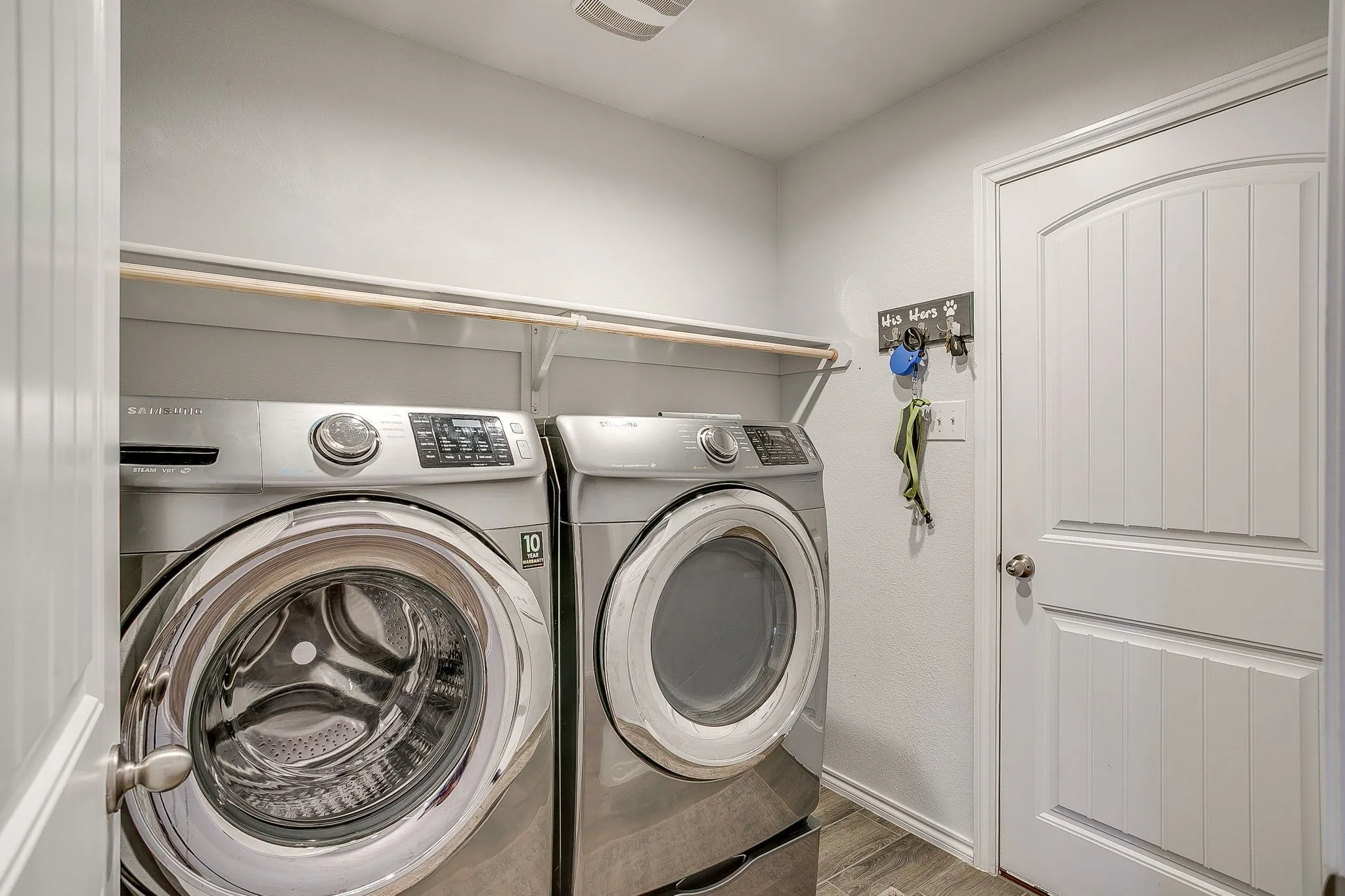 Laundry area with wood-finish flooring, white walls, and a built-in shelf