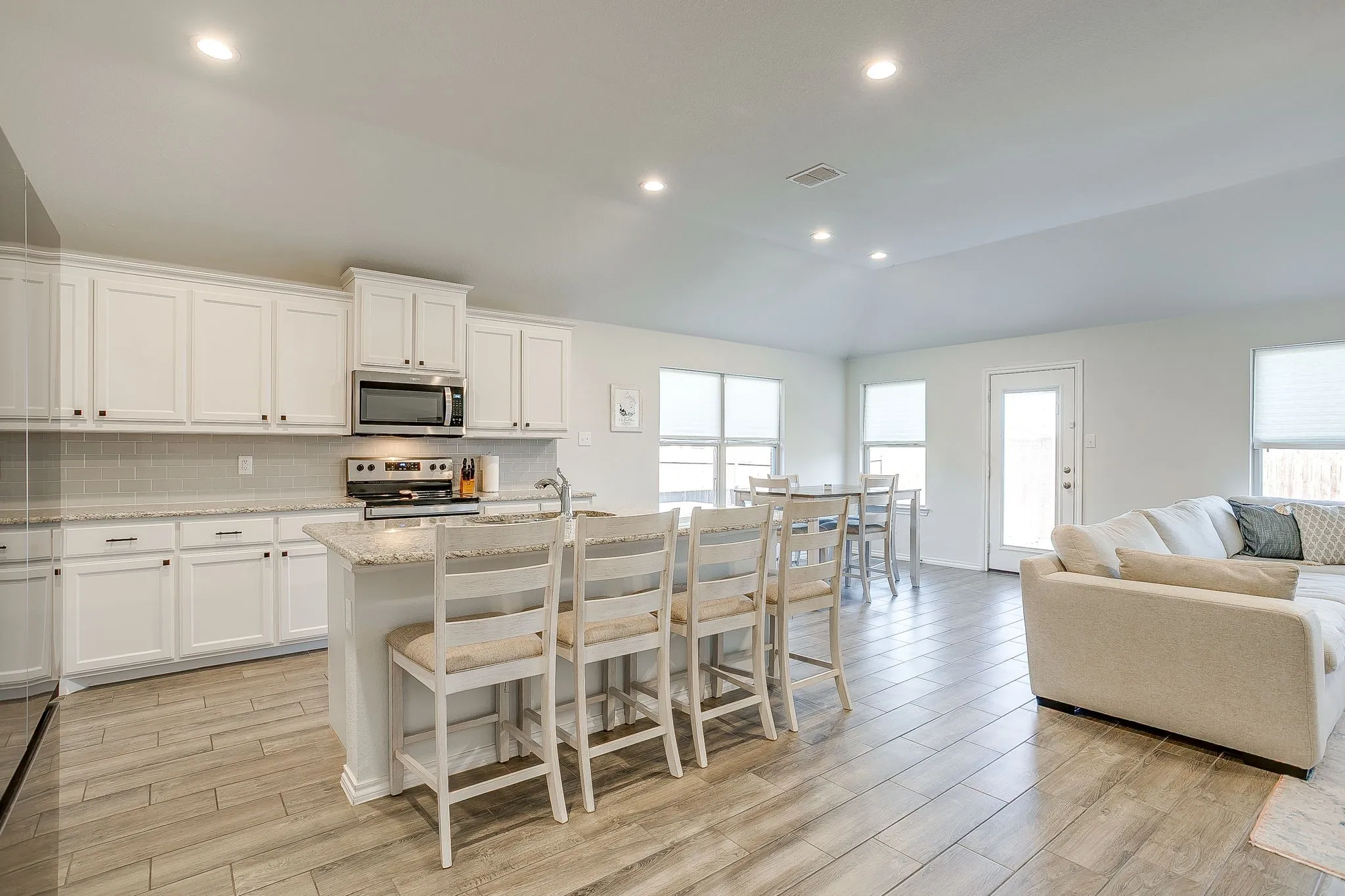 Kitchen with white cabinetry, stainless steel appliances, and a central island with countertop seating