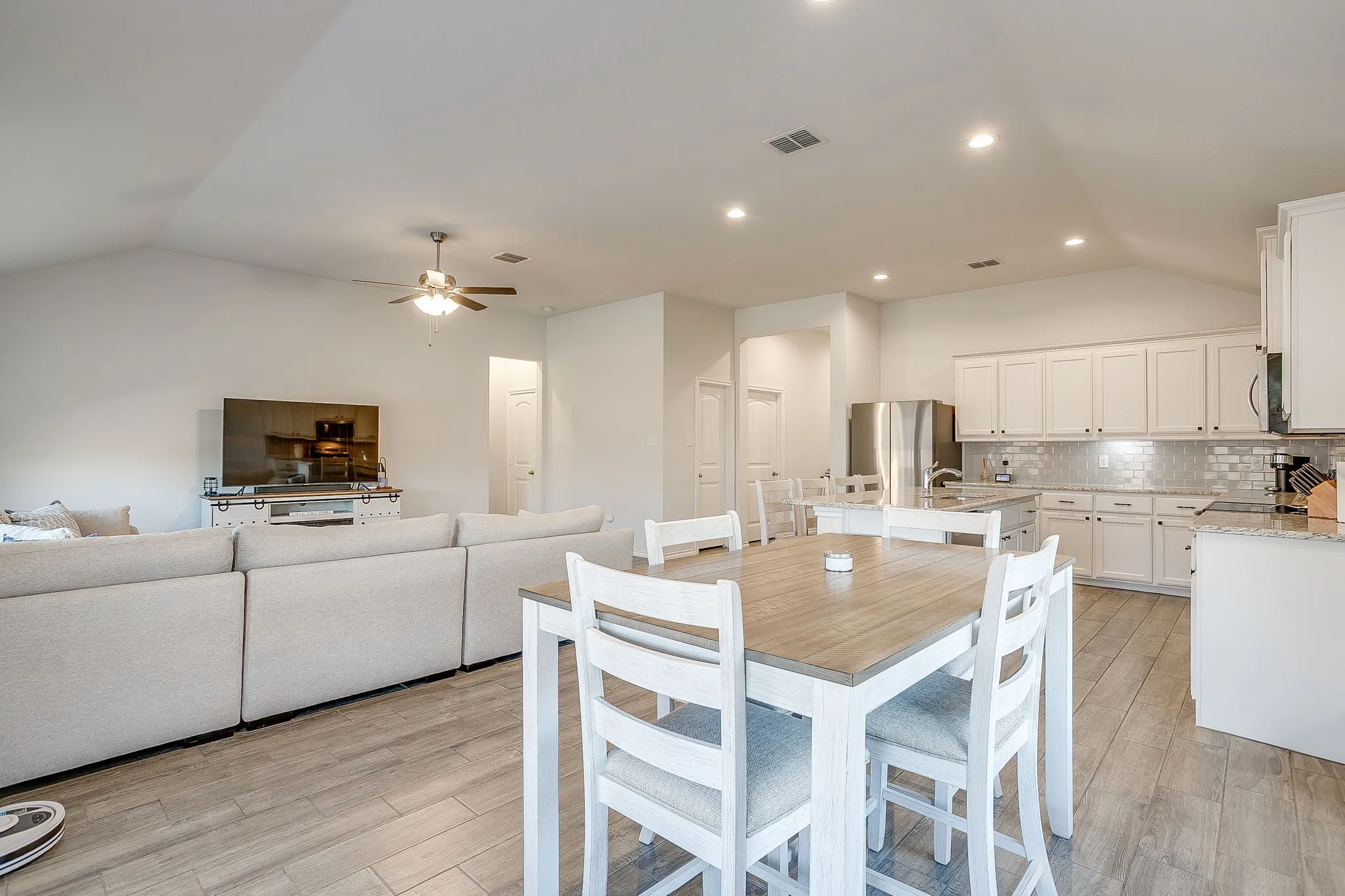Open-concept living space featuring wood-finish flooring, vaulted ceiling, and recessed lighting