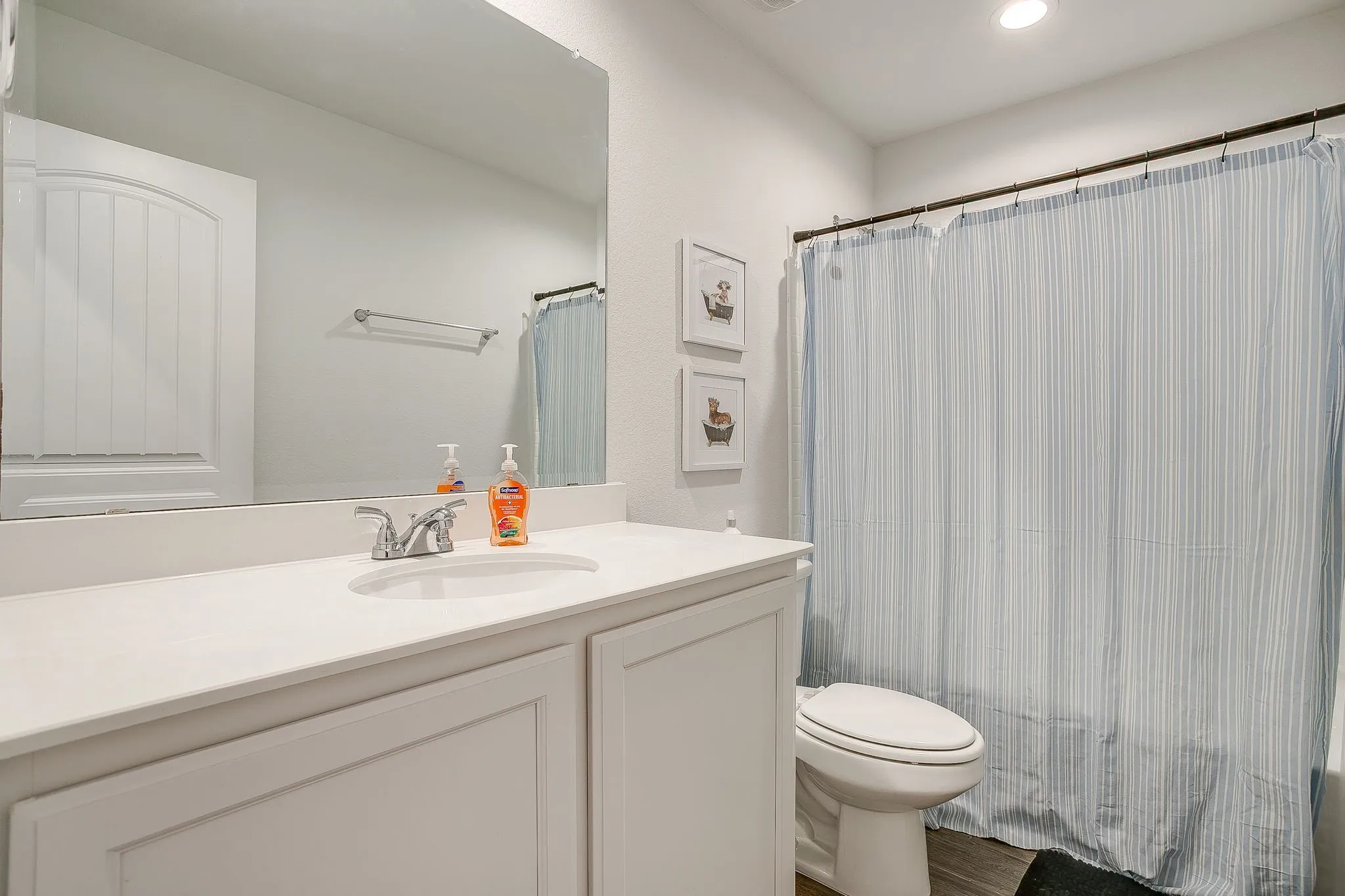 Bathroom featuring a single vanity with an integrated sink, polished chrome faucet, and a large wall-mounted mirror