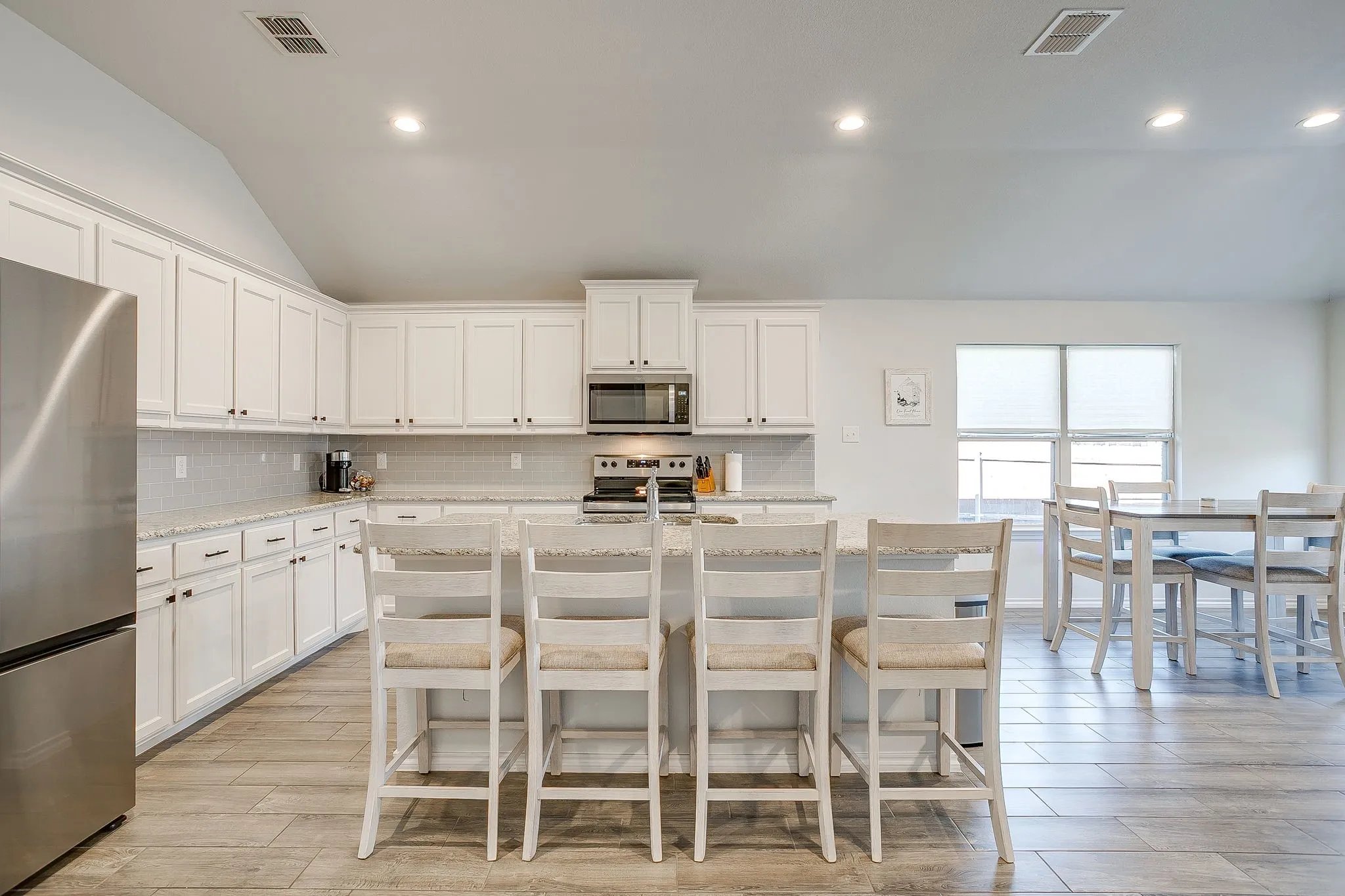 Kitchen featuring white cabinetry, stainless steel appliances, speckled countertops, and wood-finish flooring