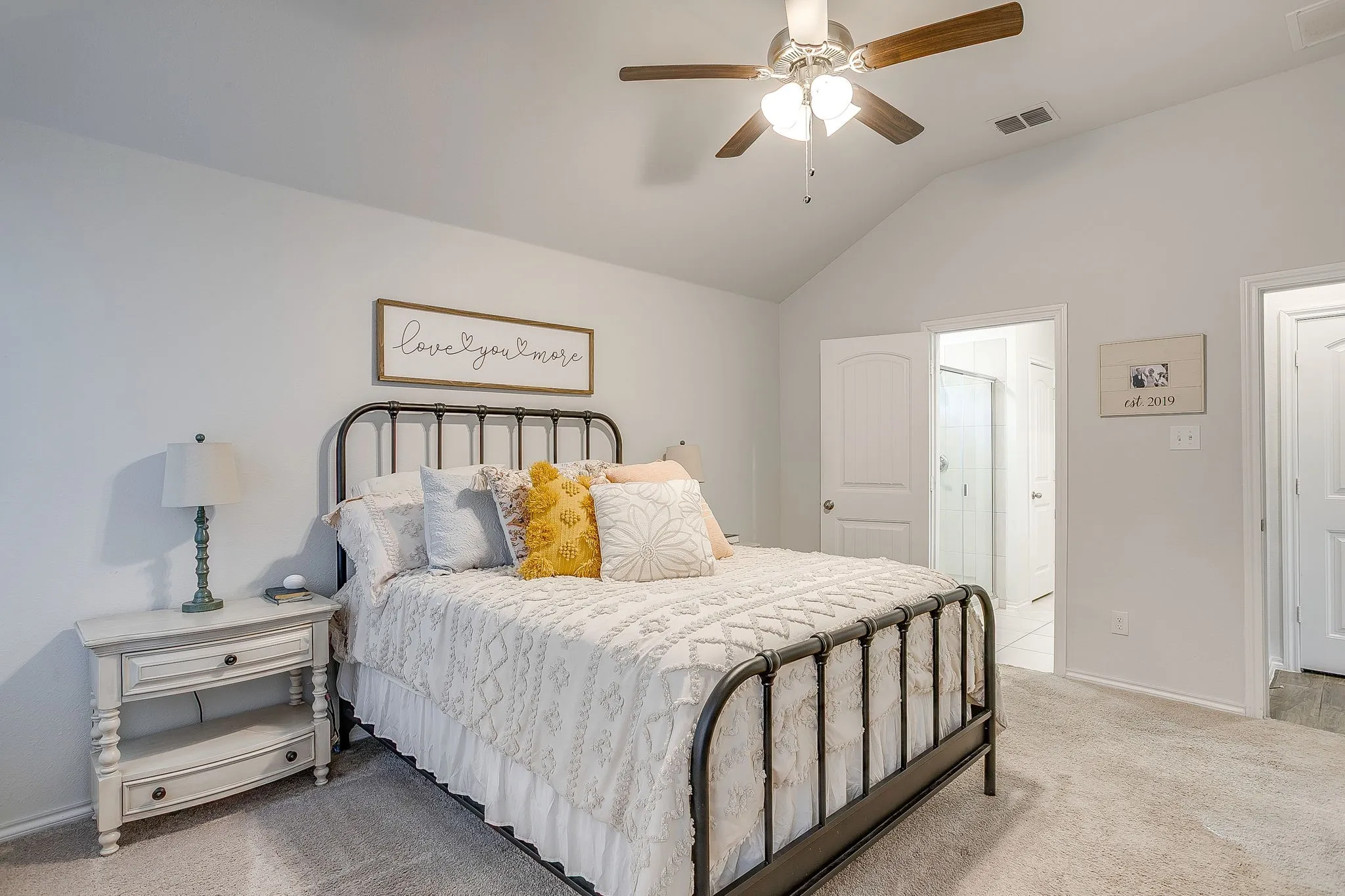 Vaulted ceiling, ceiling fan with light fixture, carpet flooring, white trim, and white panel doors