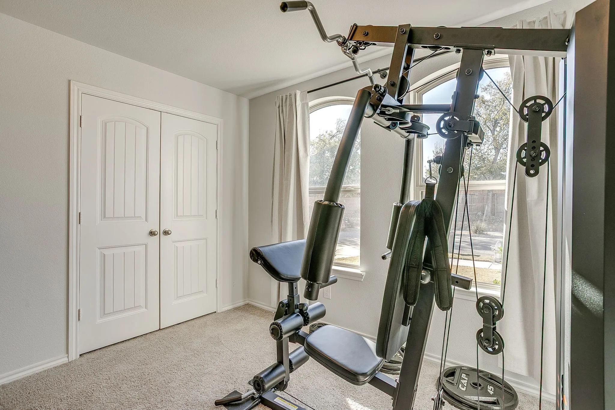 Arched windows with window treatments, light gray wall paint, and white trim