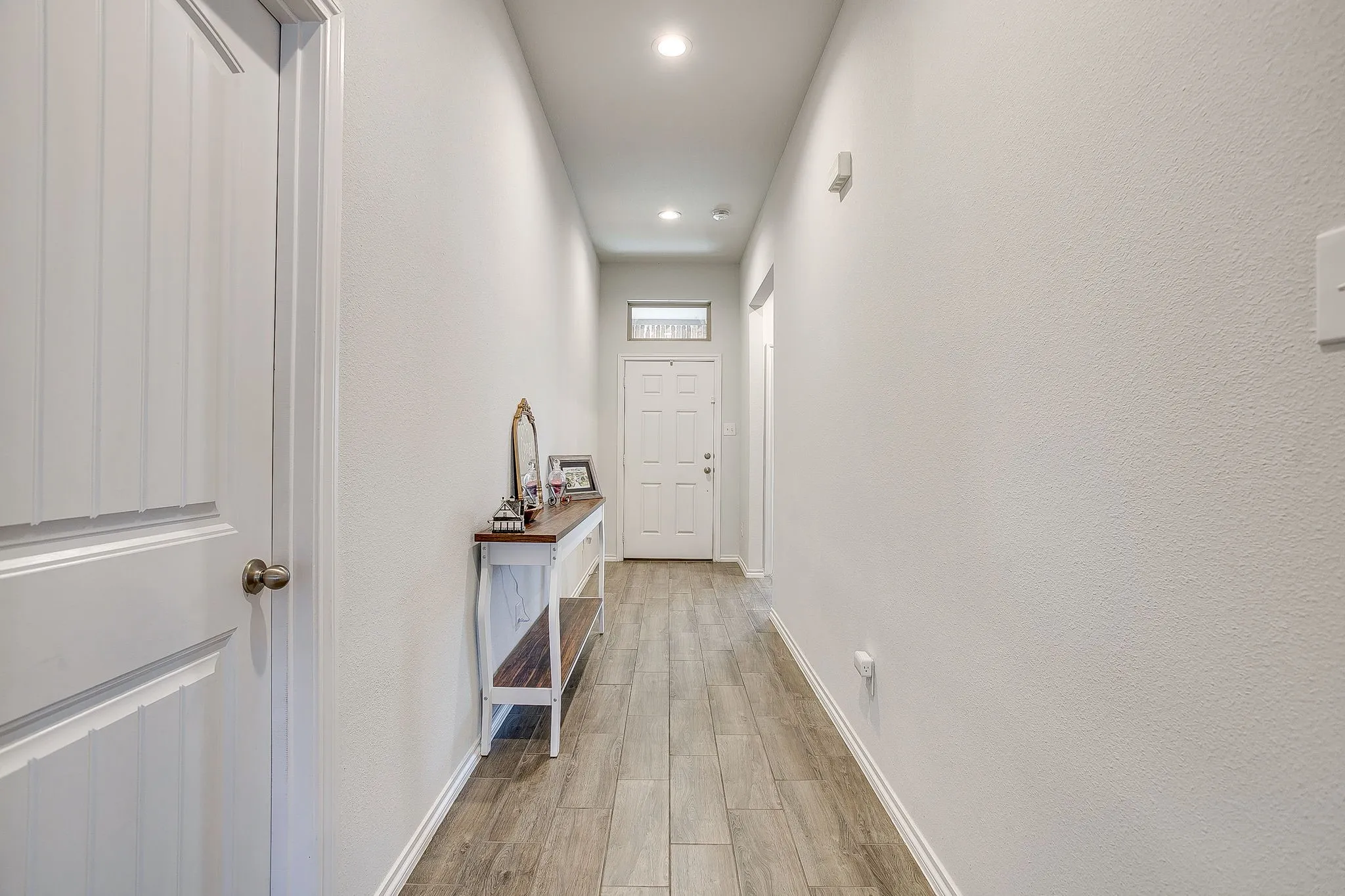 Wood-finish plank flooring, recessed ceiling lighting, and white paneled doors