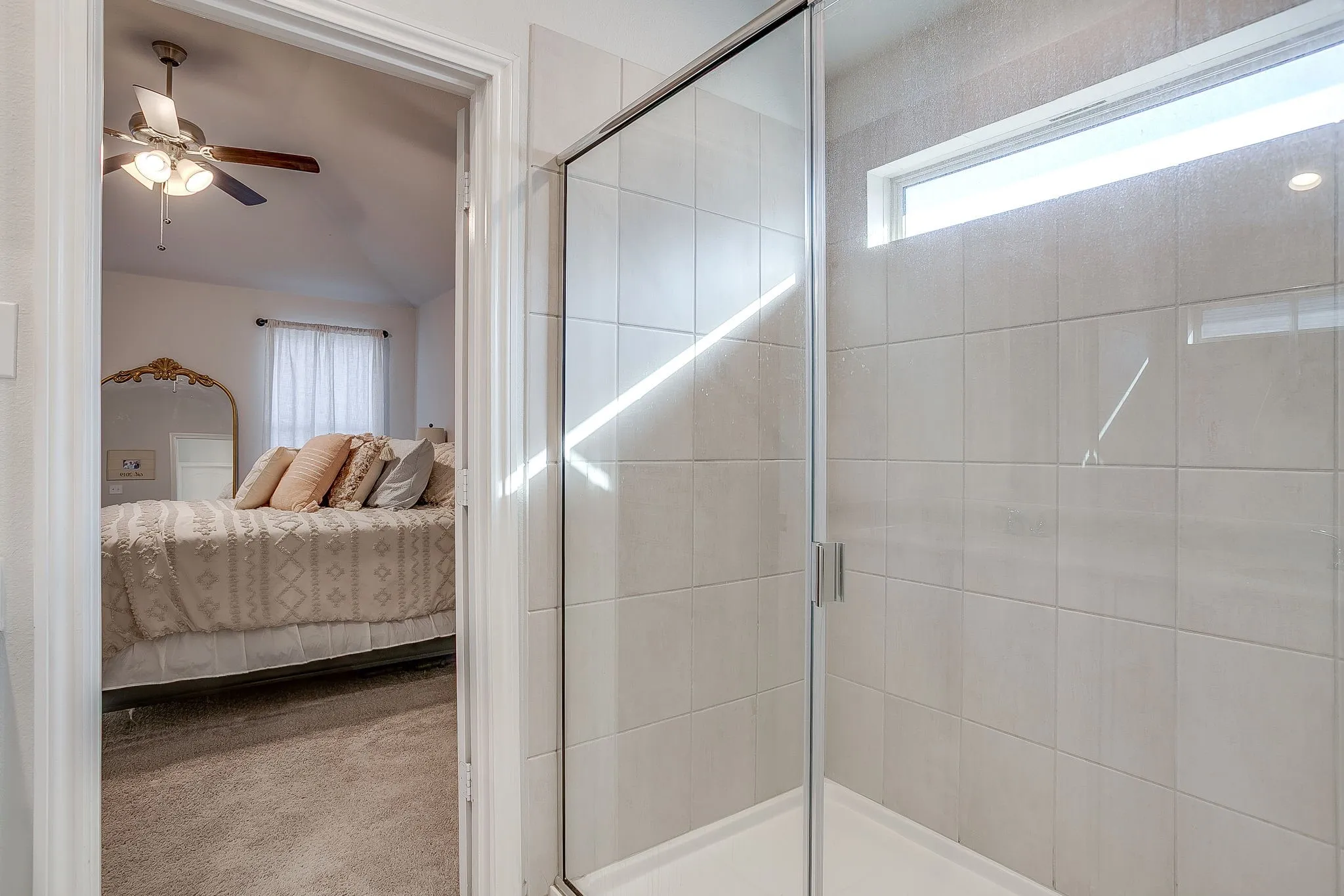 Glass-enclosed shower with square tile surround and a transom window