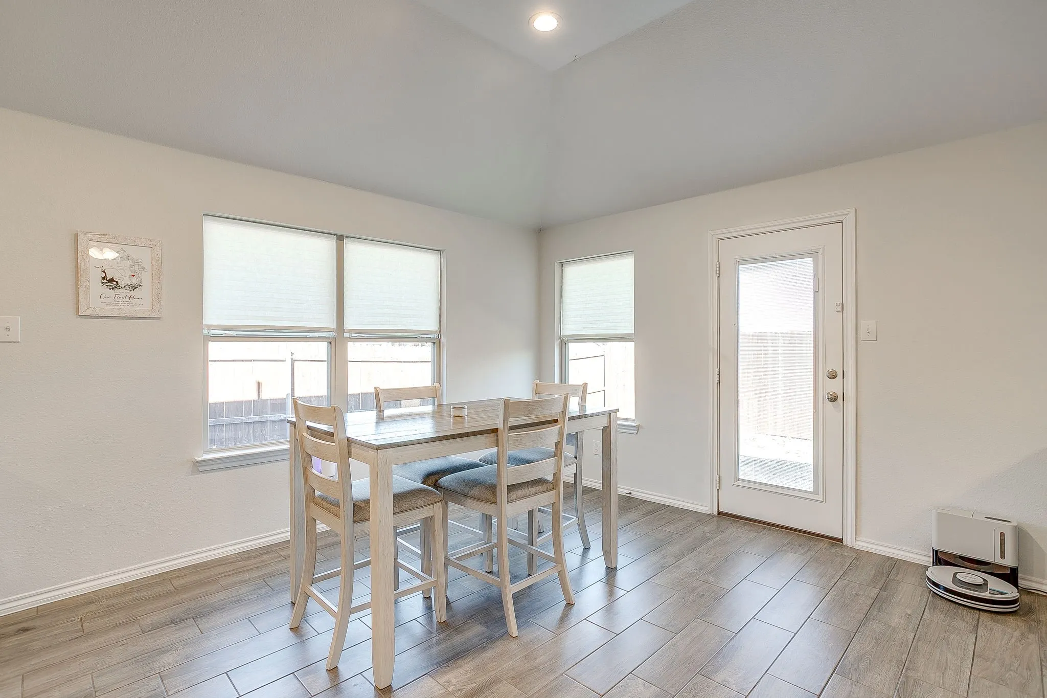 Wood-finish flooring, vaulted ceiling with recessed lighting, and multiple windows with blinds