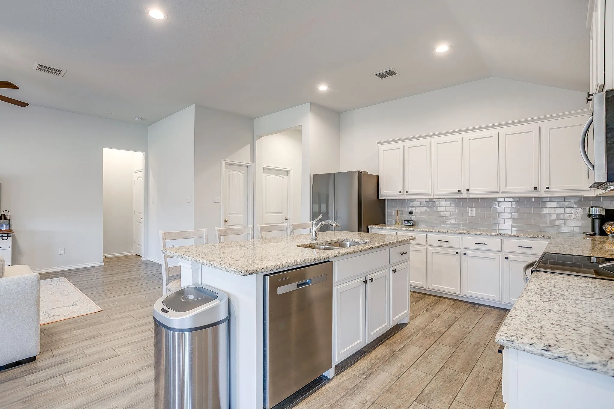 Kitchen featuring a center island, white cabinetry, granite-style countertops, stainless steel appliances, and a tiled backsplash