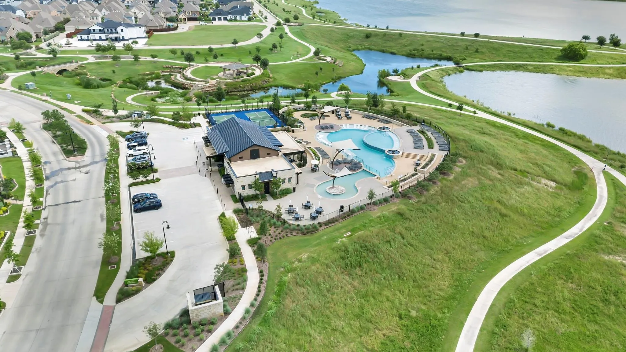 Recreational facilities featuring a tennis court, multiple swimming pools, and a clubhouse with exterior seating