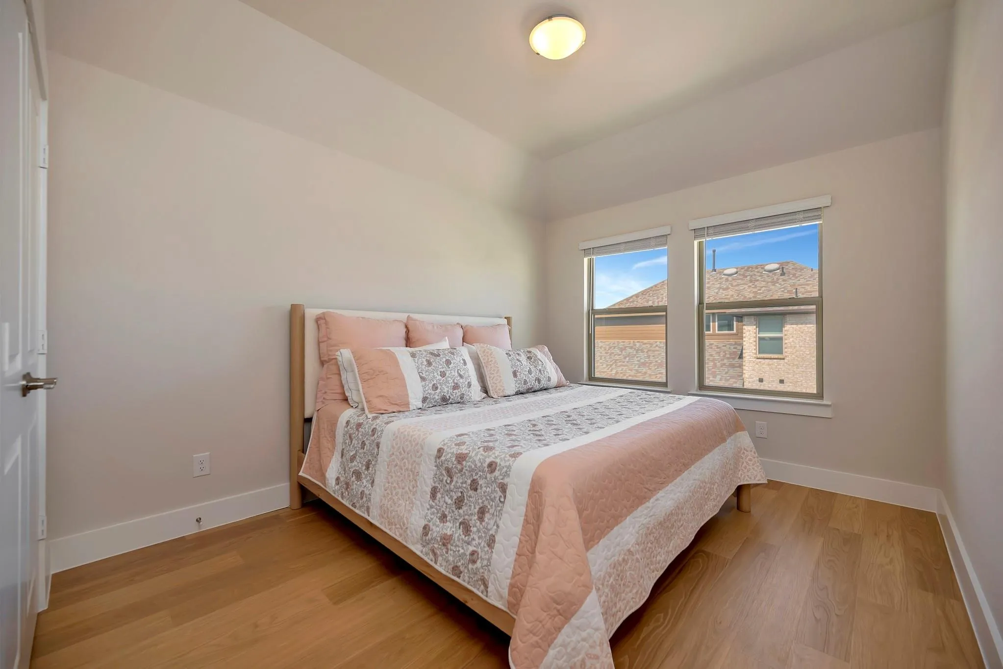 Recessed ceiling, neutral wall paint, wood-finish flooring, two windows with blinds, and white trim