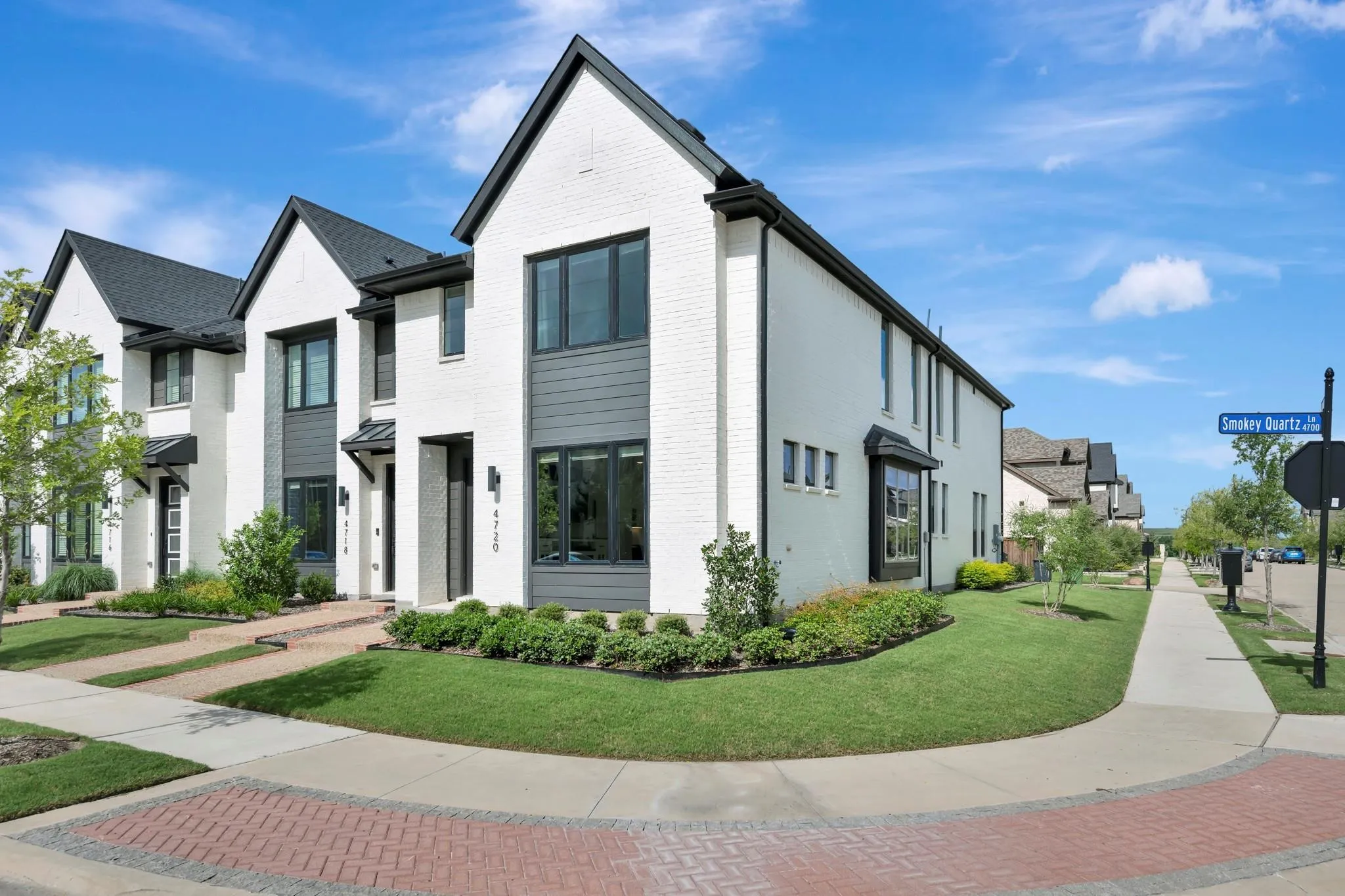 White brick exterior with dark trim, dark shingle roof, and a bay window