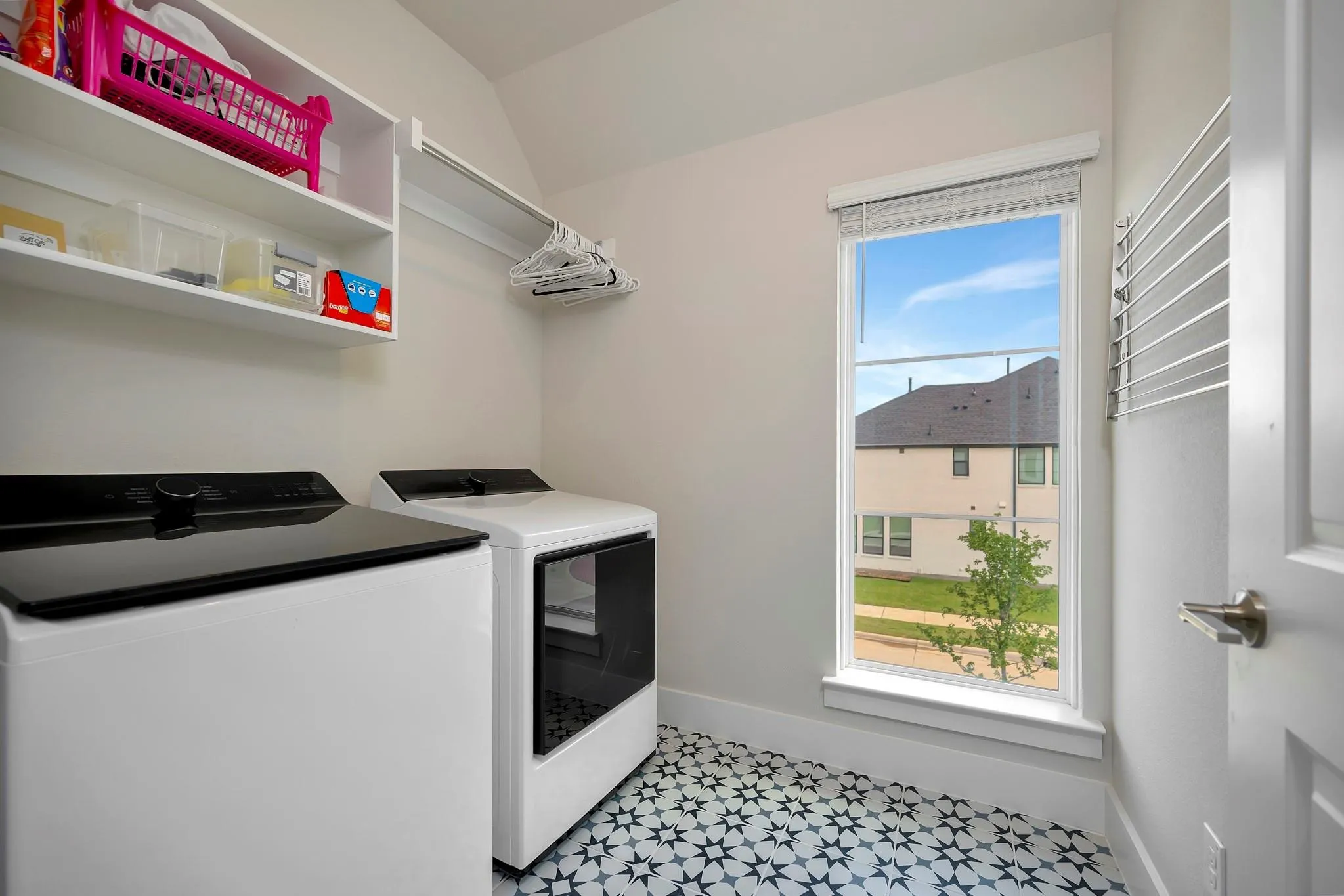 Laundry area featuring patterned floor tile, a single window, built-in shelving, and a hanging rod