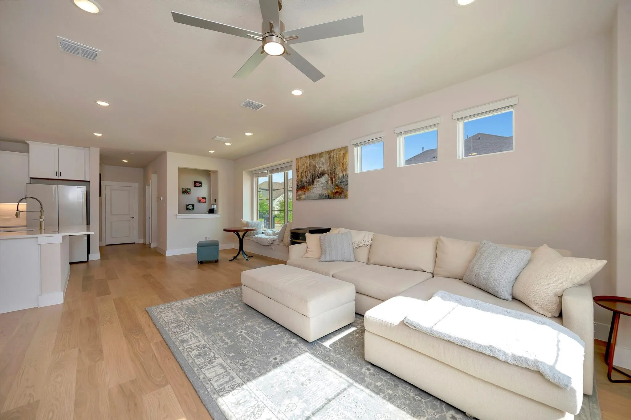 Recessed lighting throughout, light wood-finish flooring, and a modern ceiling fan