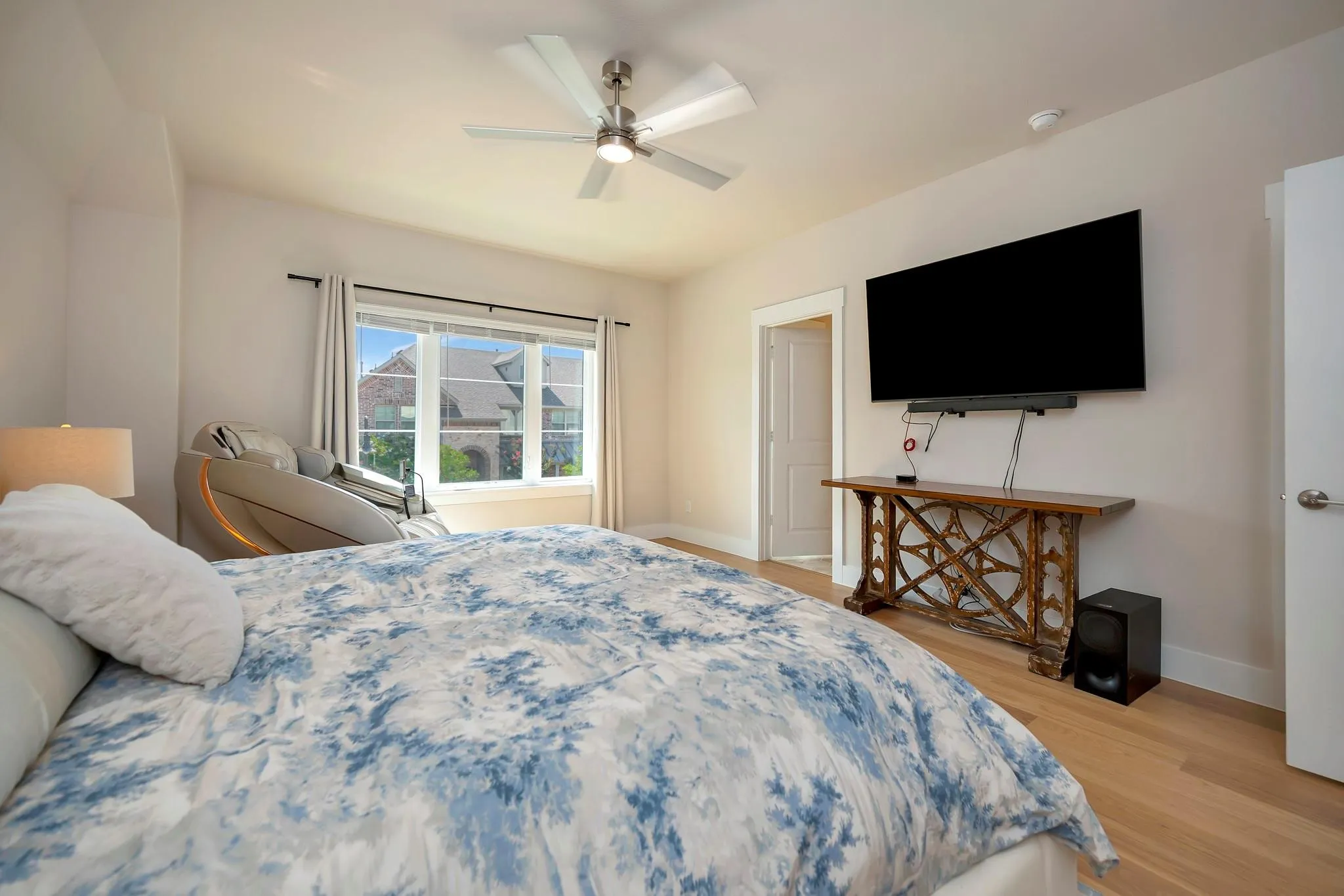 Light wood-finish flooring, ceiling fan with integrated lighting, recessed lighting, and a transom window