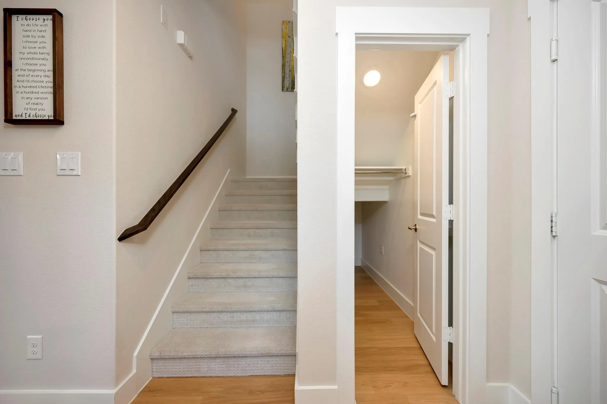 Carpeted staircase with a dark wood handrail, leading to an upper level