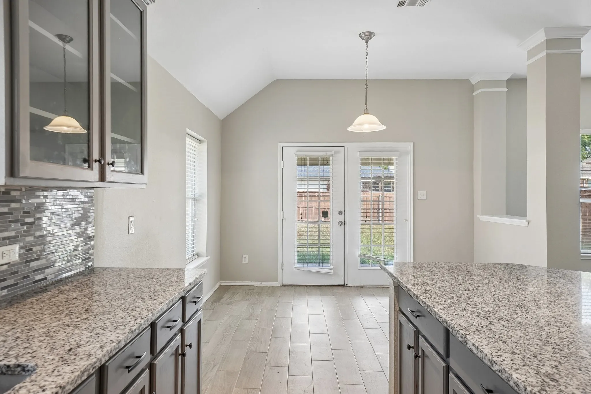 Kitchen featuring granite countertops, glass-front upper cabinetry, mosaic tile backsplash, and wood-finish flooring