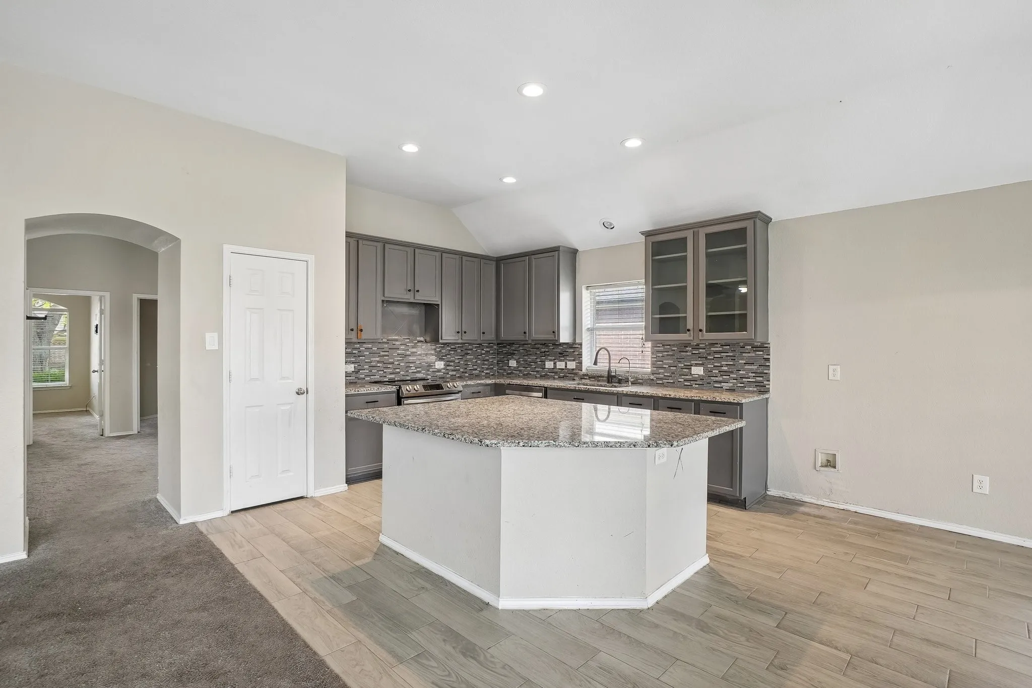 Kitchen featuring an island, gray cabinetry, granite countertops, tile backsplash, and recessed lighting