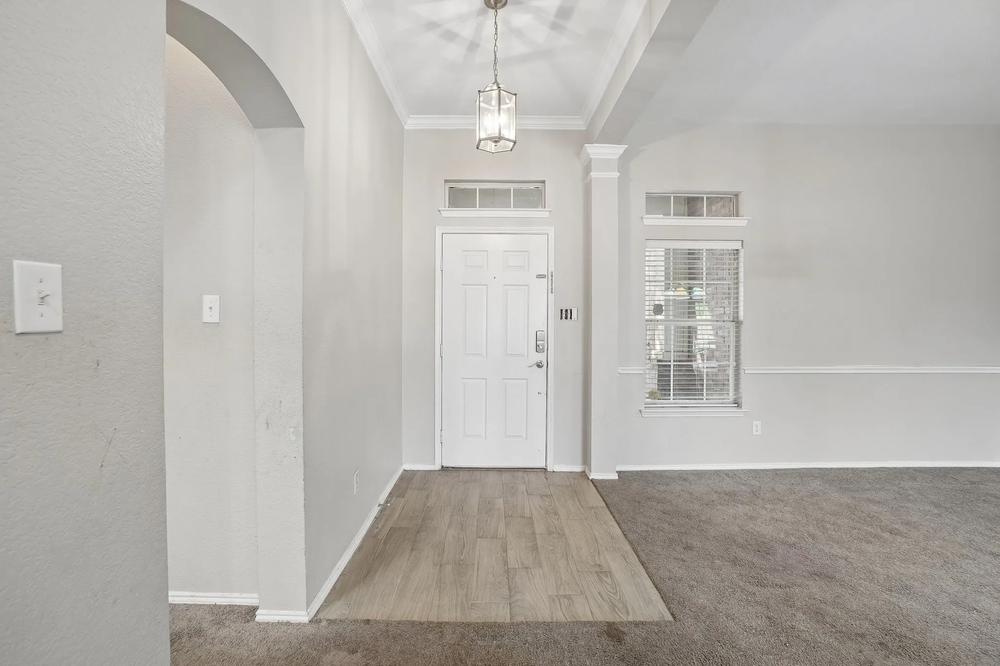 Entry with wood-finish flooring, recessed ceiling, and a decorative light fixture