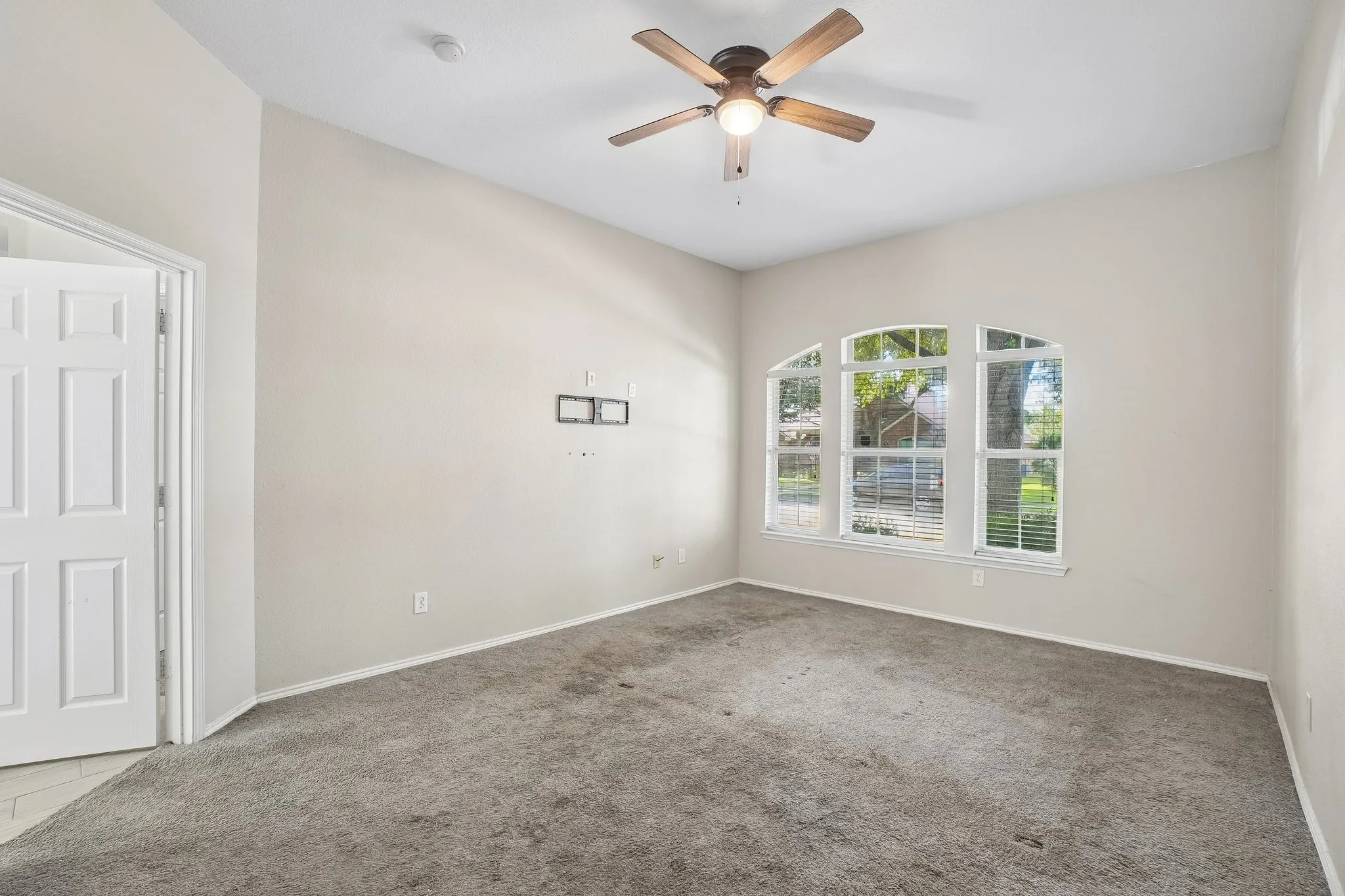 Arched window set, ceiling fan with integrated lighting, paneled interior door, and light-toned wall paint