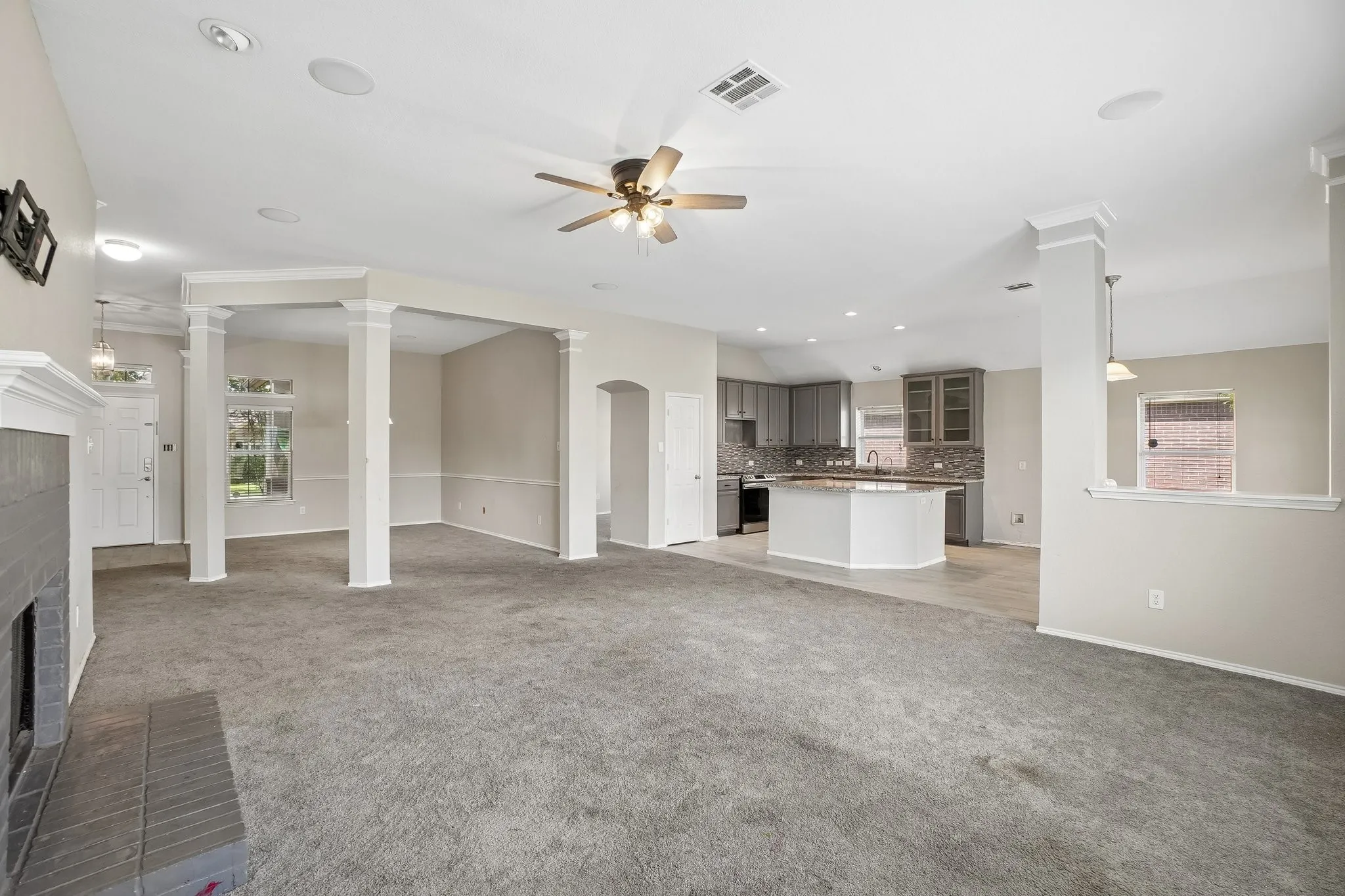 Expansive open-concept living space with vaulted ceilings, a central fireplace, and recessed lighting