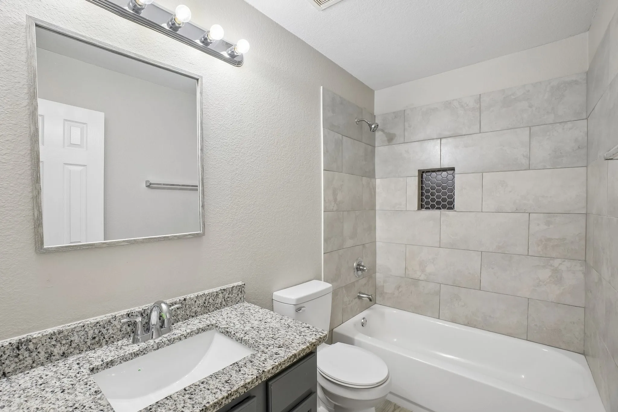 Vanity with speckled countertop, undermount sink, and chrome faucet