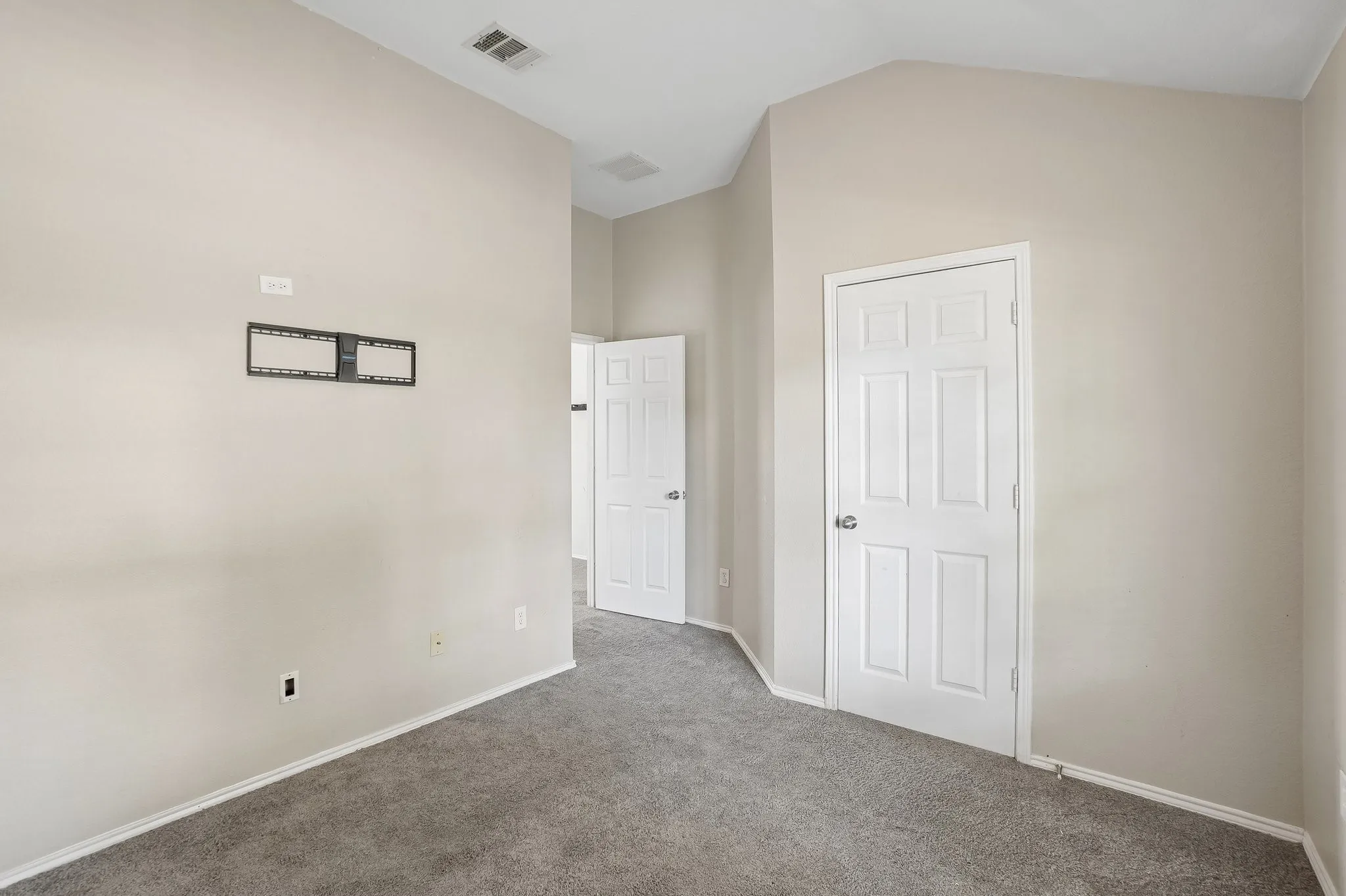 Neutral-toned walls, vaulted ceiling, and gray carpeting