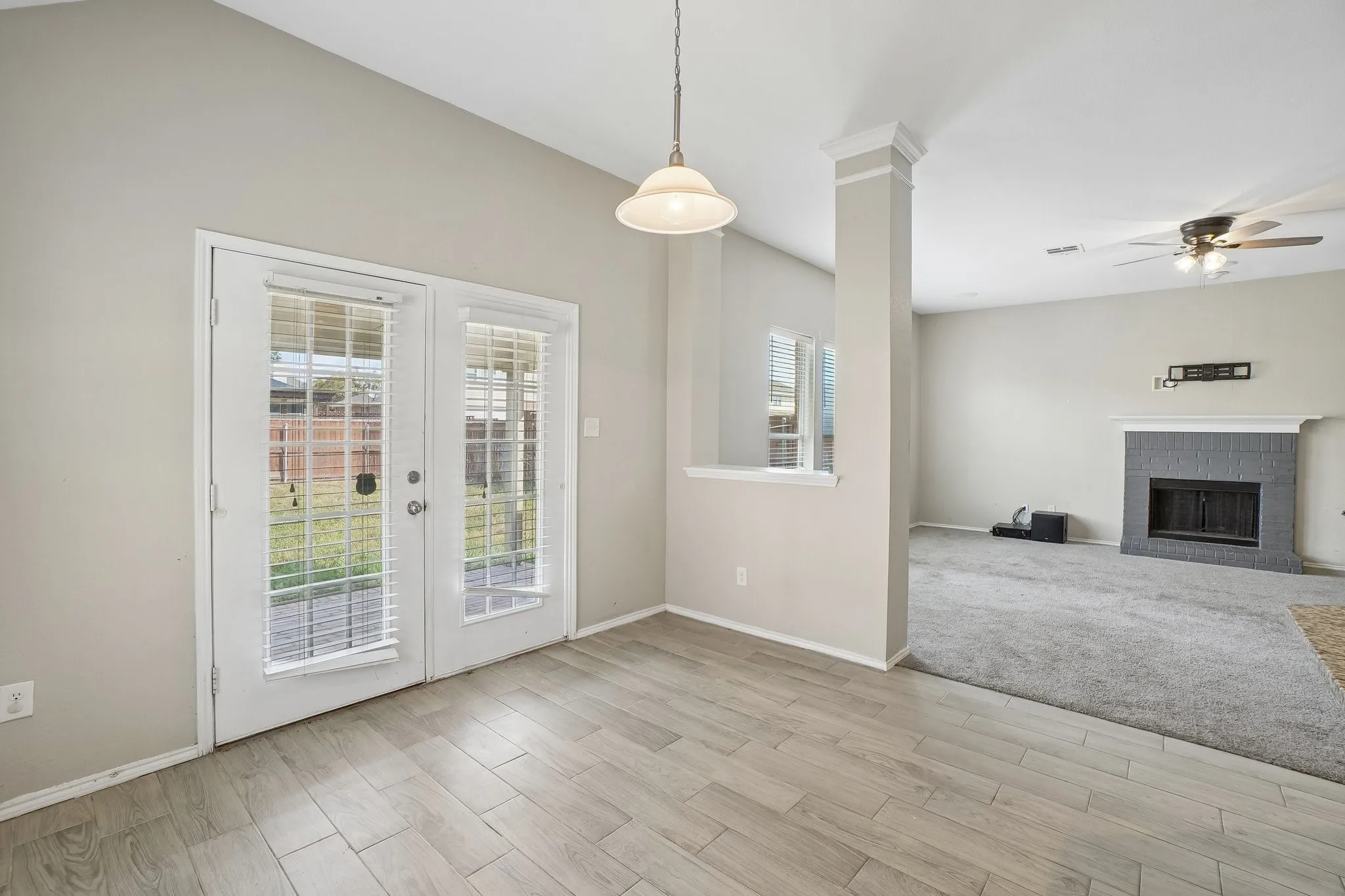 Vaulted ceiling, wood-finish flooring, white double patio doors, recessed fireplace, and ceiling fan
