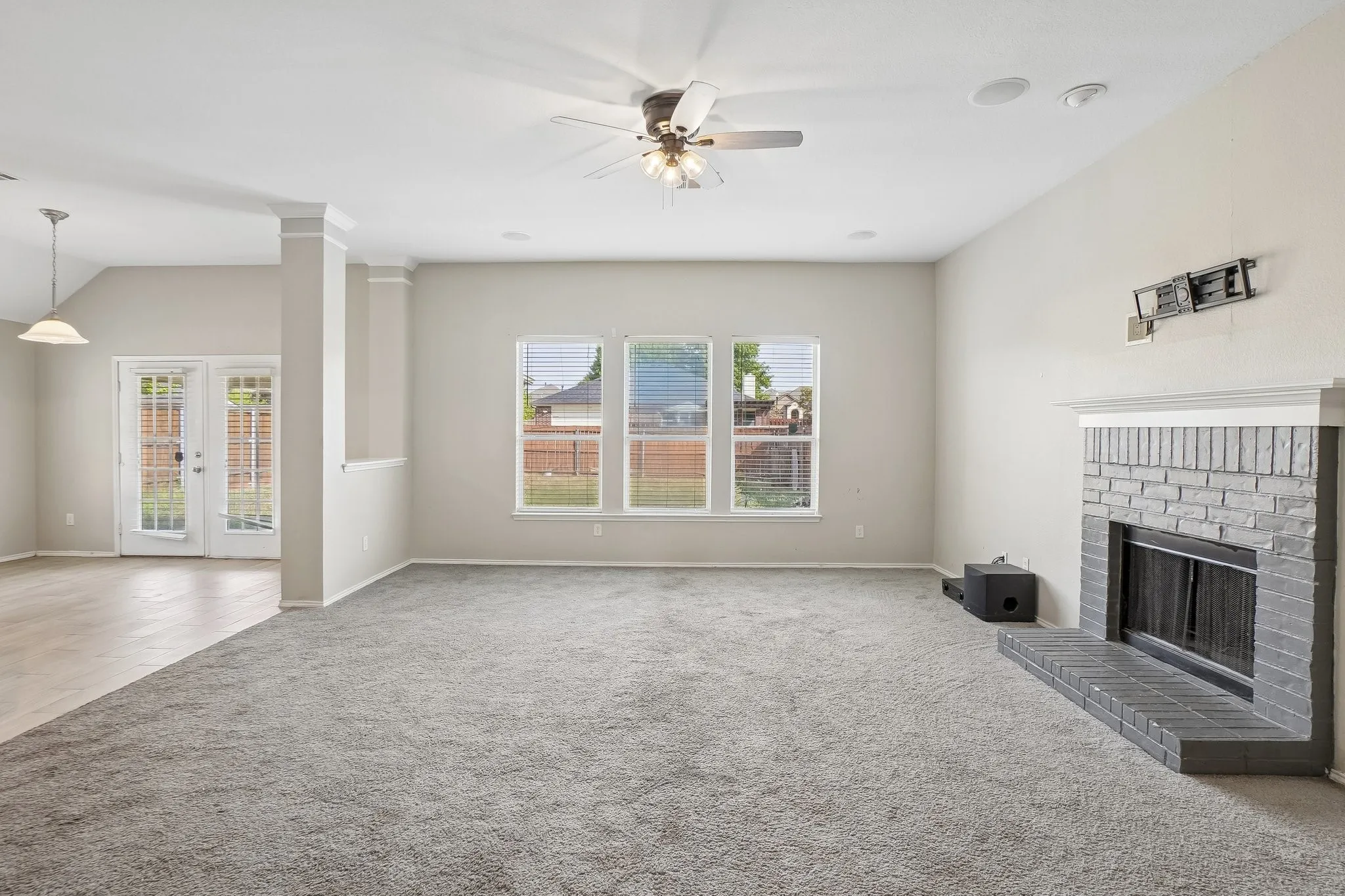 Carpeted living area with a ceiling fan, a brick fireplace, and three large windows