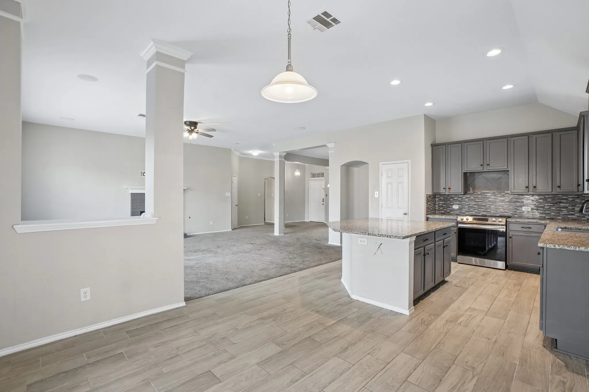 Kitchen featuring light wood-finish flooring, gray cabinetry, speckled countertops, and a tiled backsplash