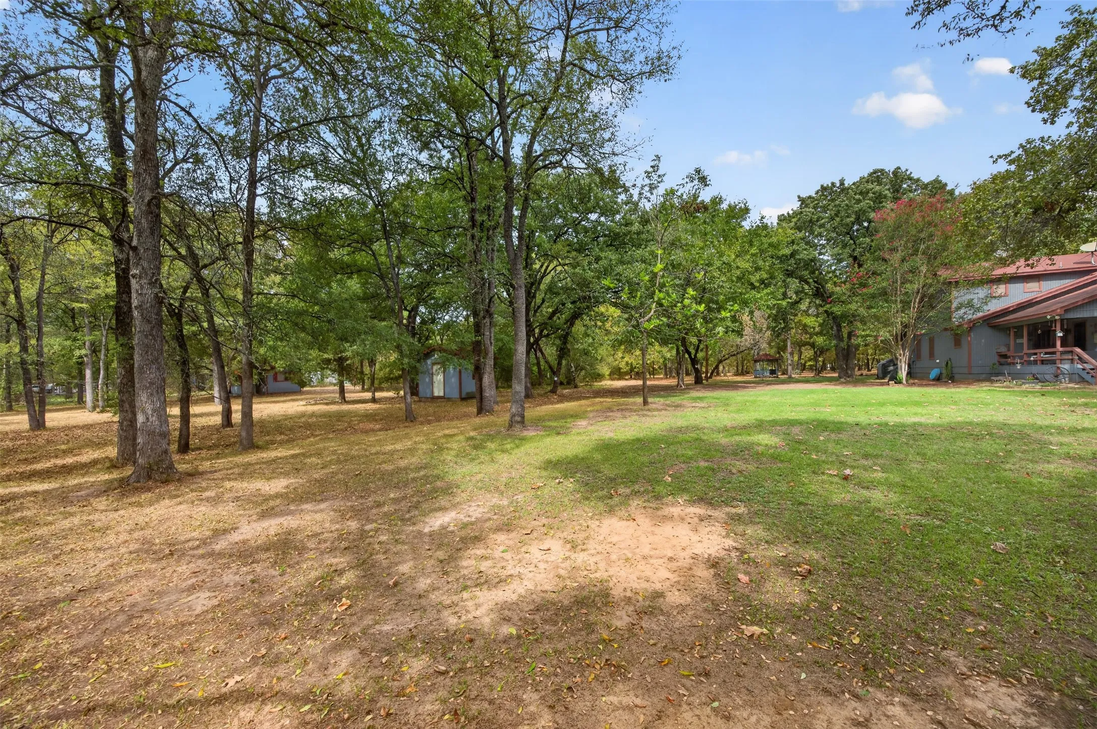 Expansive property featuring a mix of mature trees, open grassy areas, and a visible outbuilding