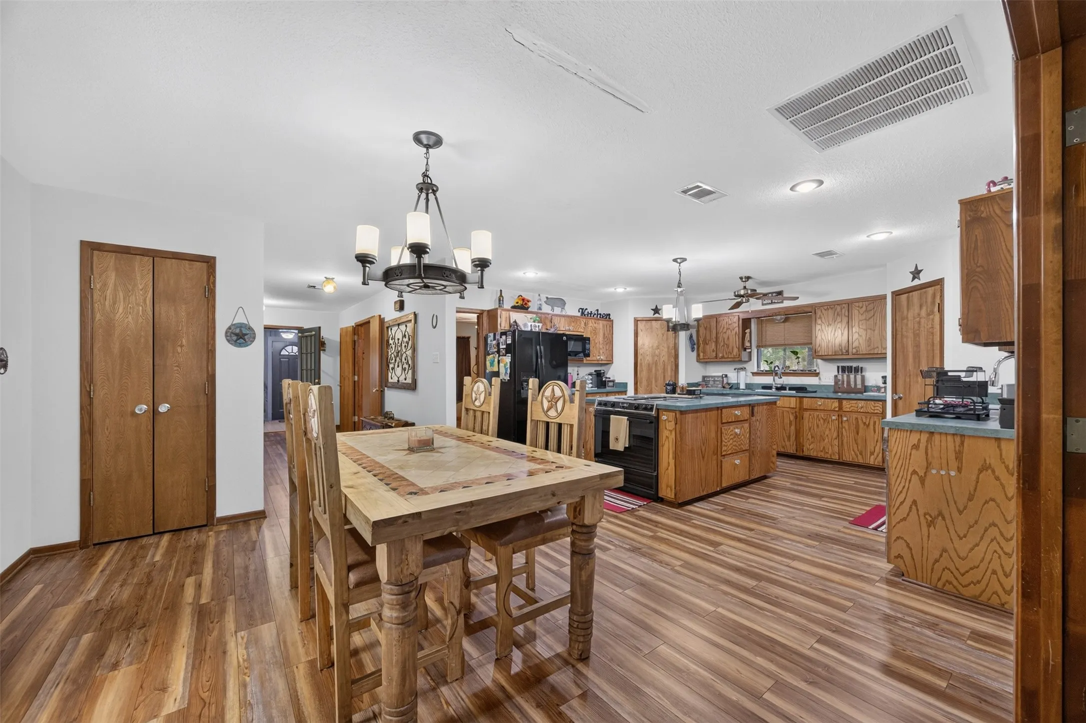 Wood-finish flooring throughout, kitchen with wood cabinetry, and a ceiling fan