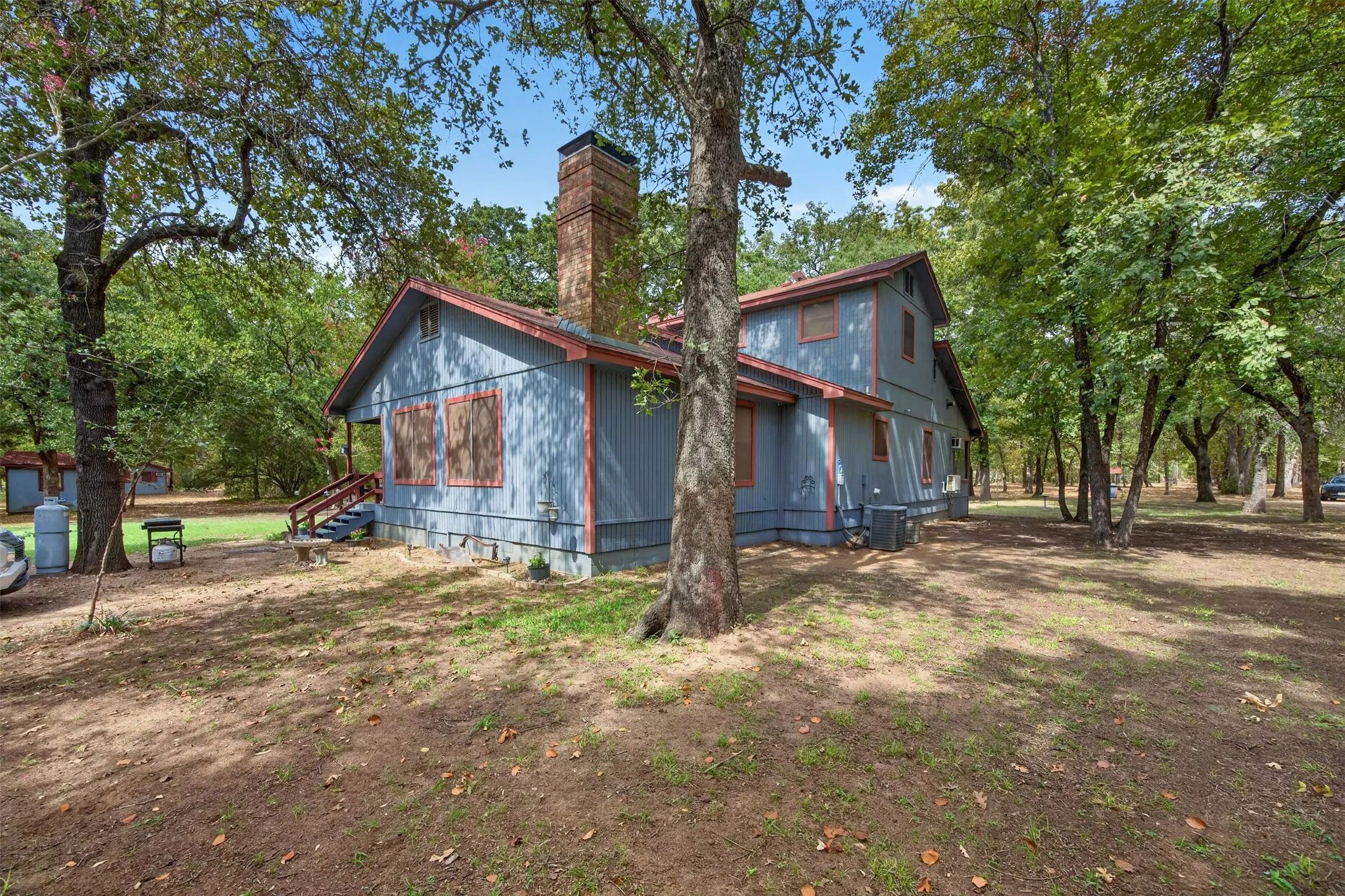 Two-story exterior with a brick chimney, shed roof, and wood siding