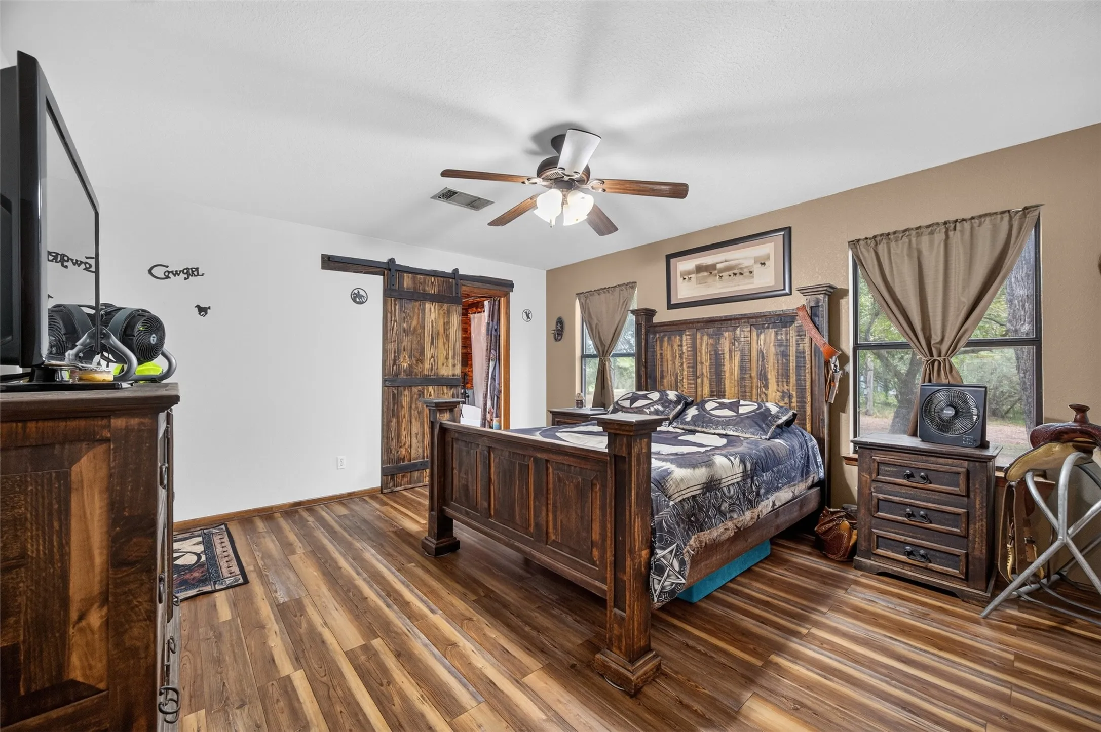 Wood-finish flooring throughout, ceiling fan with integrated lighting, and a barn door entry
