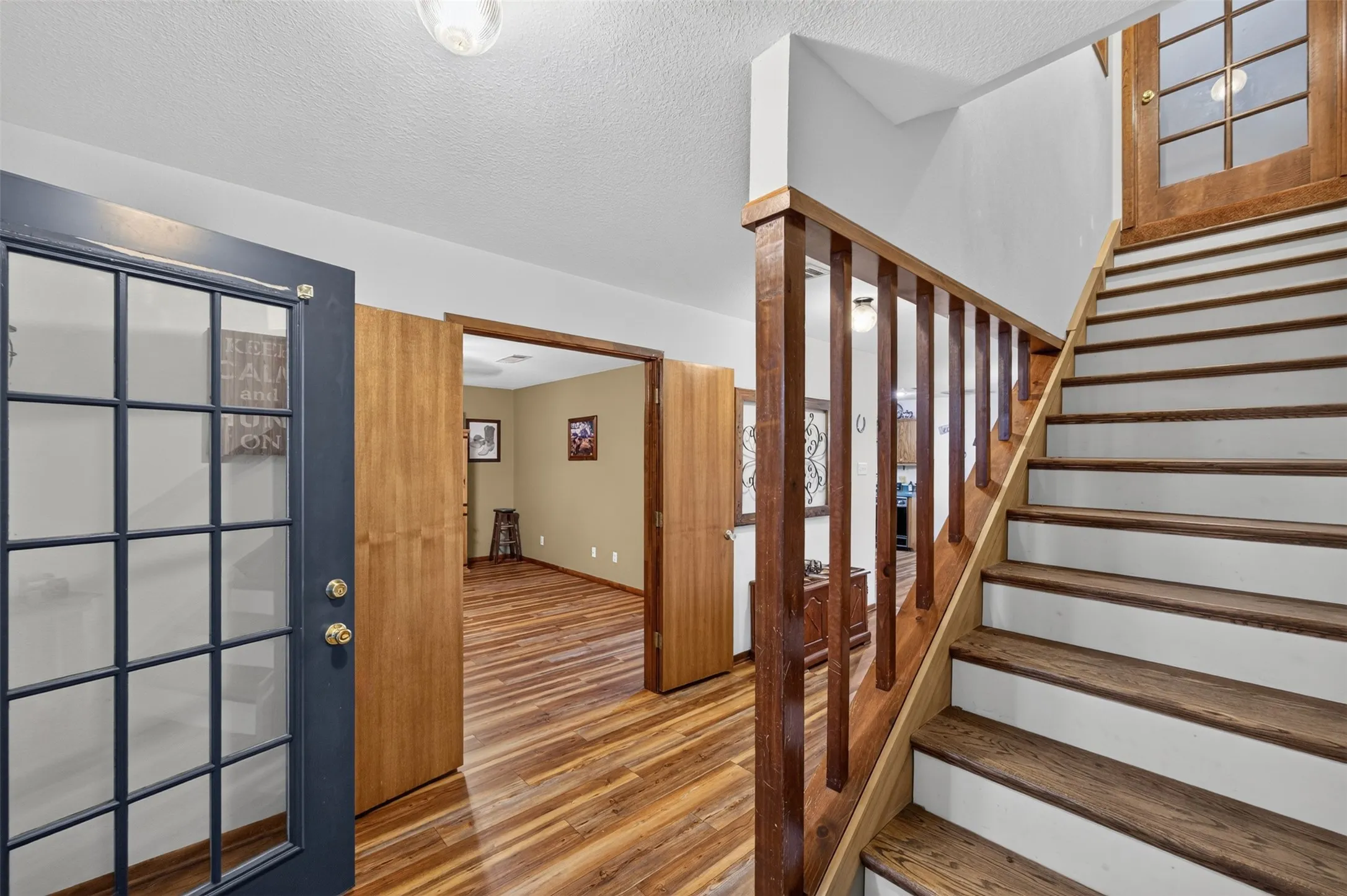 Wood-finish flooring throughout, wood staircase with white risers, and a wood handrail
