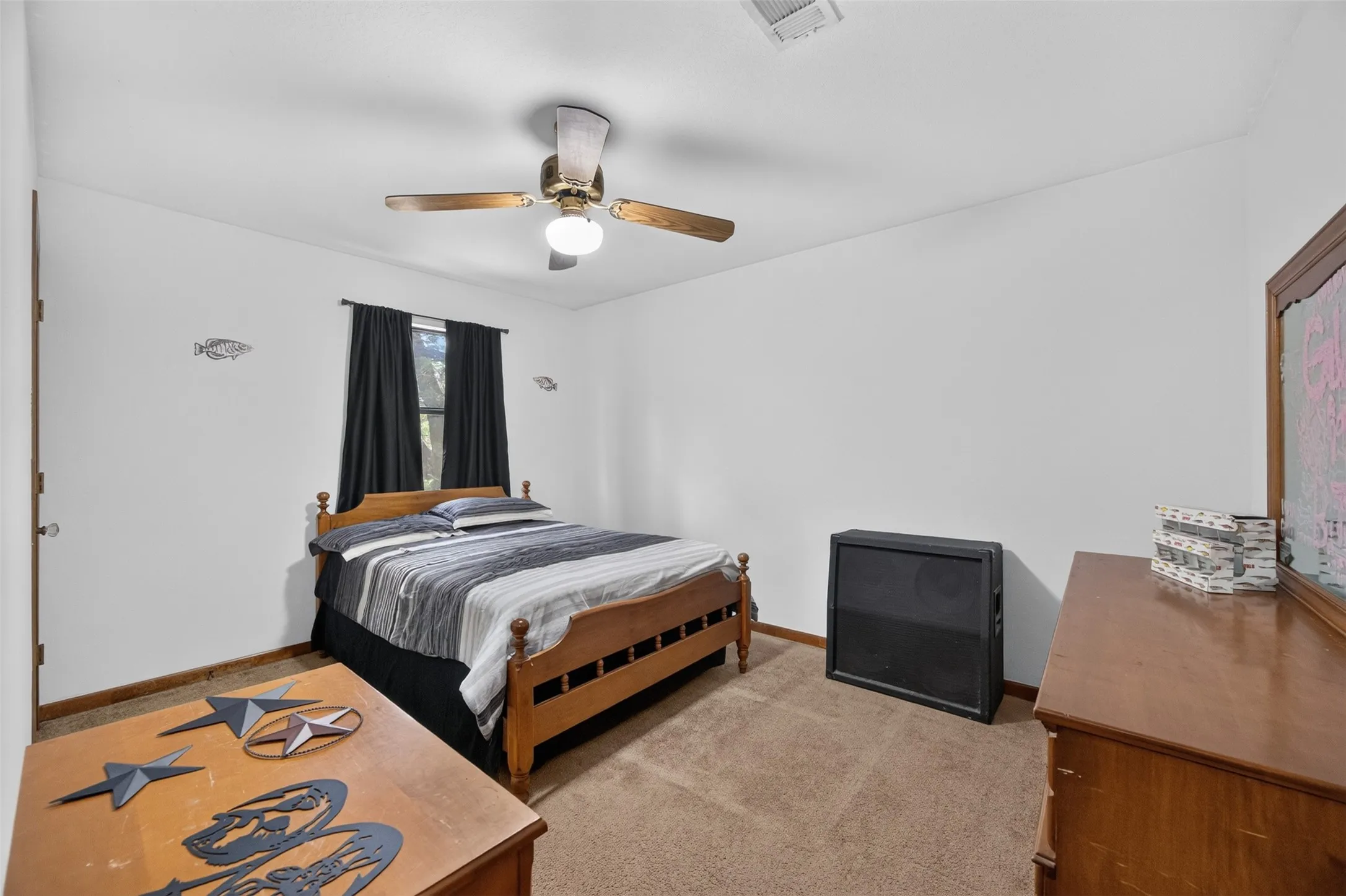 Spacious bedroom featuring hardwood-finish flooring, a wood-frame bed, ceiling fan with integrated lighting, and ample natural light from window with dark curtains