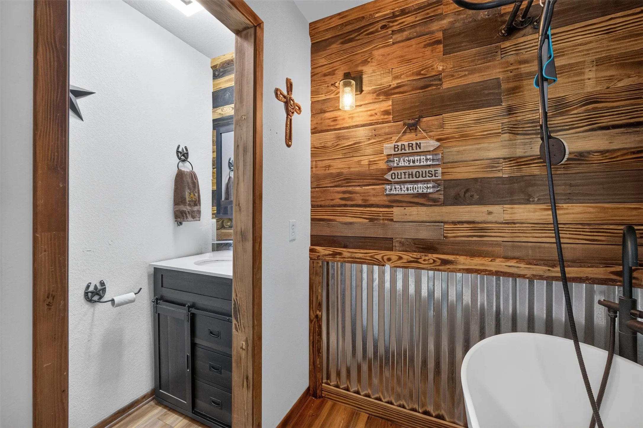 Wood-finish plank accent wall, corrugated metal wainscoting, and a freestanding soaking tub