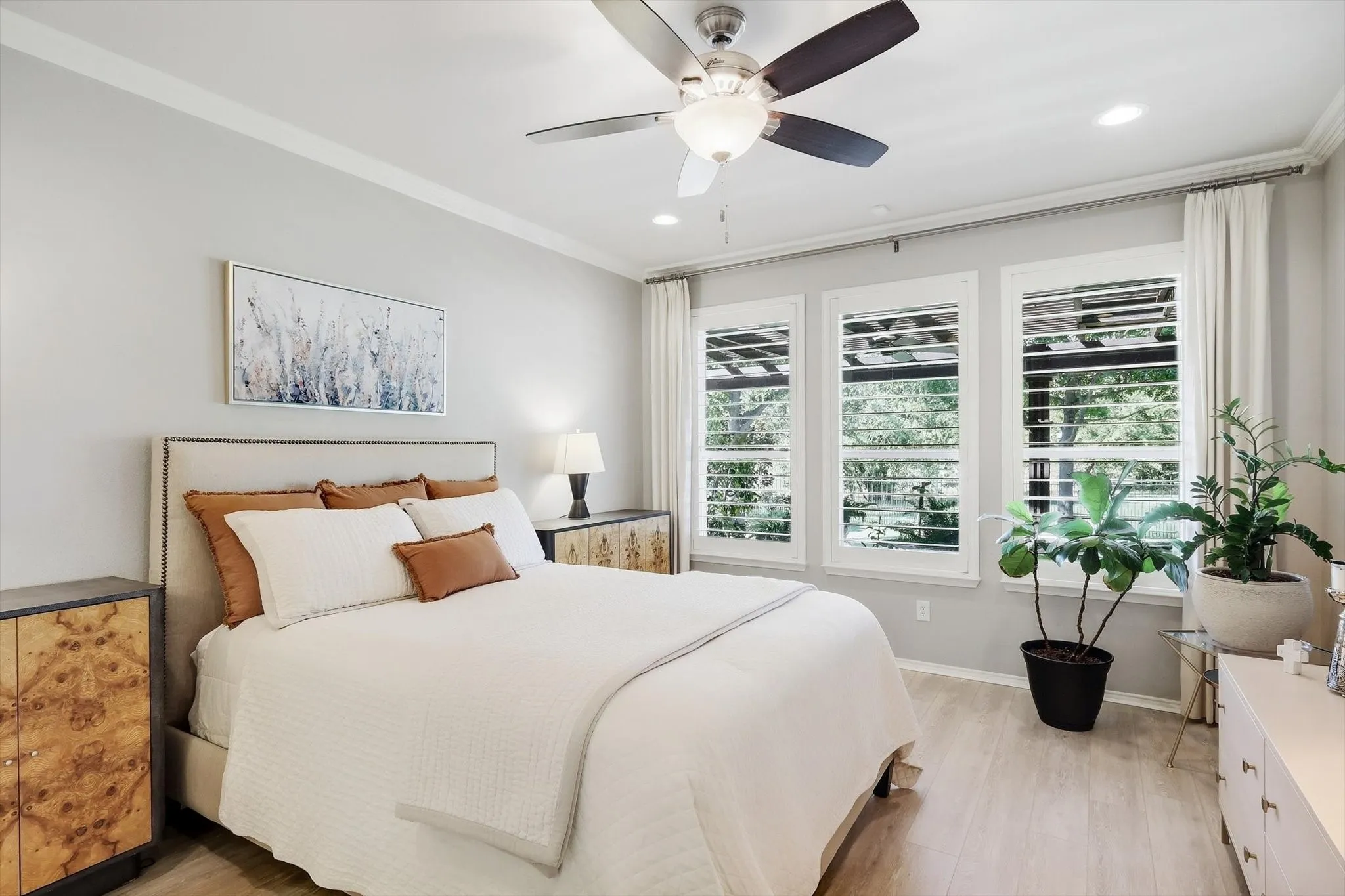 Light-toned wood-finish flooring complements the crown molding and recessed lighting