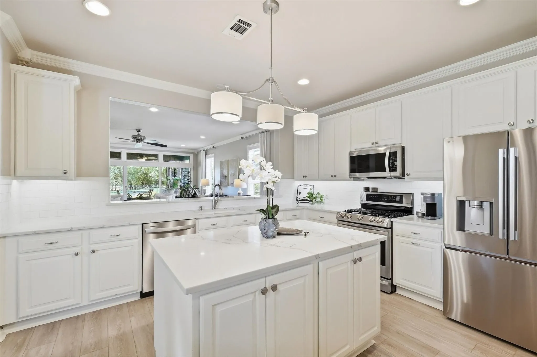 Kitchen featuring white cabinetry, stainless steel appliances, a center island with a quartz countertop, wood-finish flooring and extra cabinets