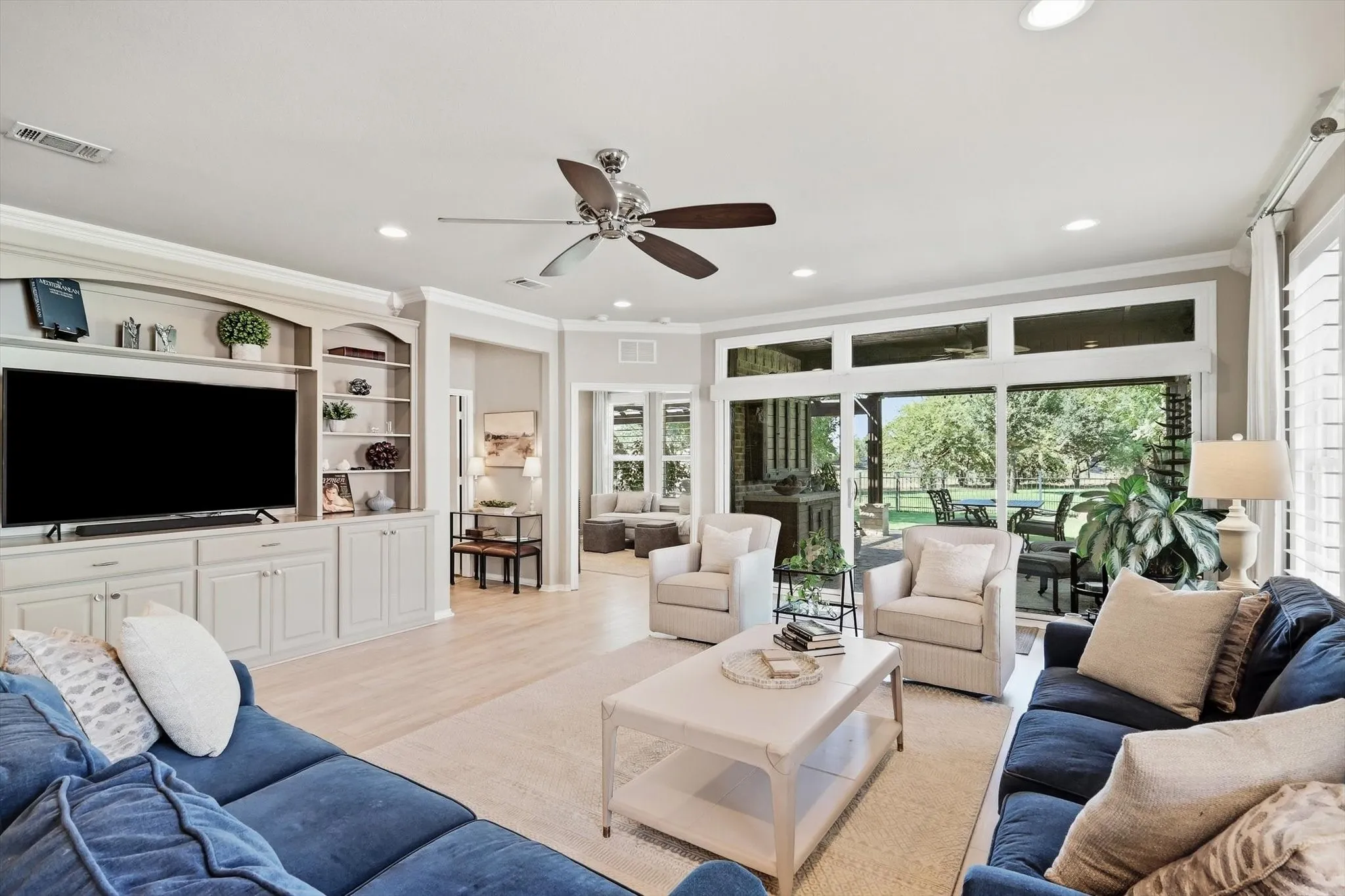 Built-in custom made cabinetry with open shelving, wood-finish flooring, ceiling fan and sliding windows with a view of golf course