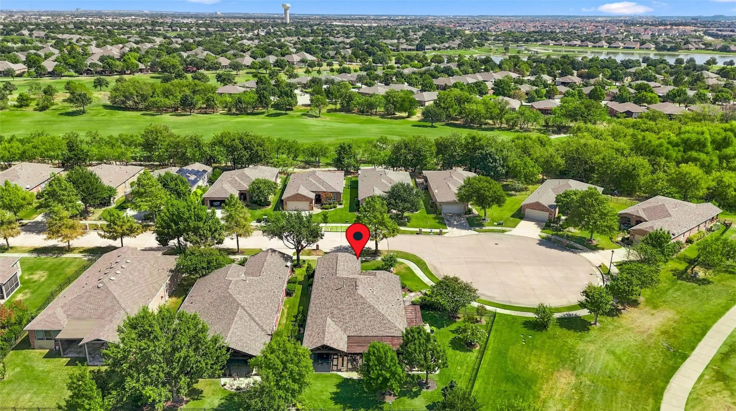 Residential property with a golf course backdrop, featuring a cul-de-sac street and established landscaping