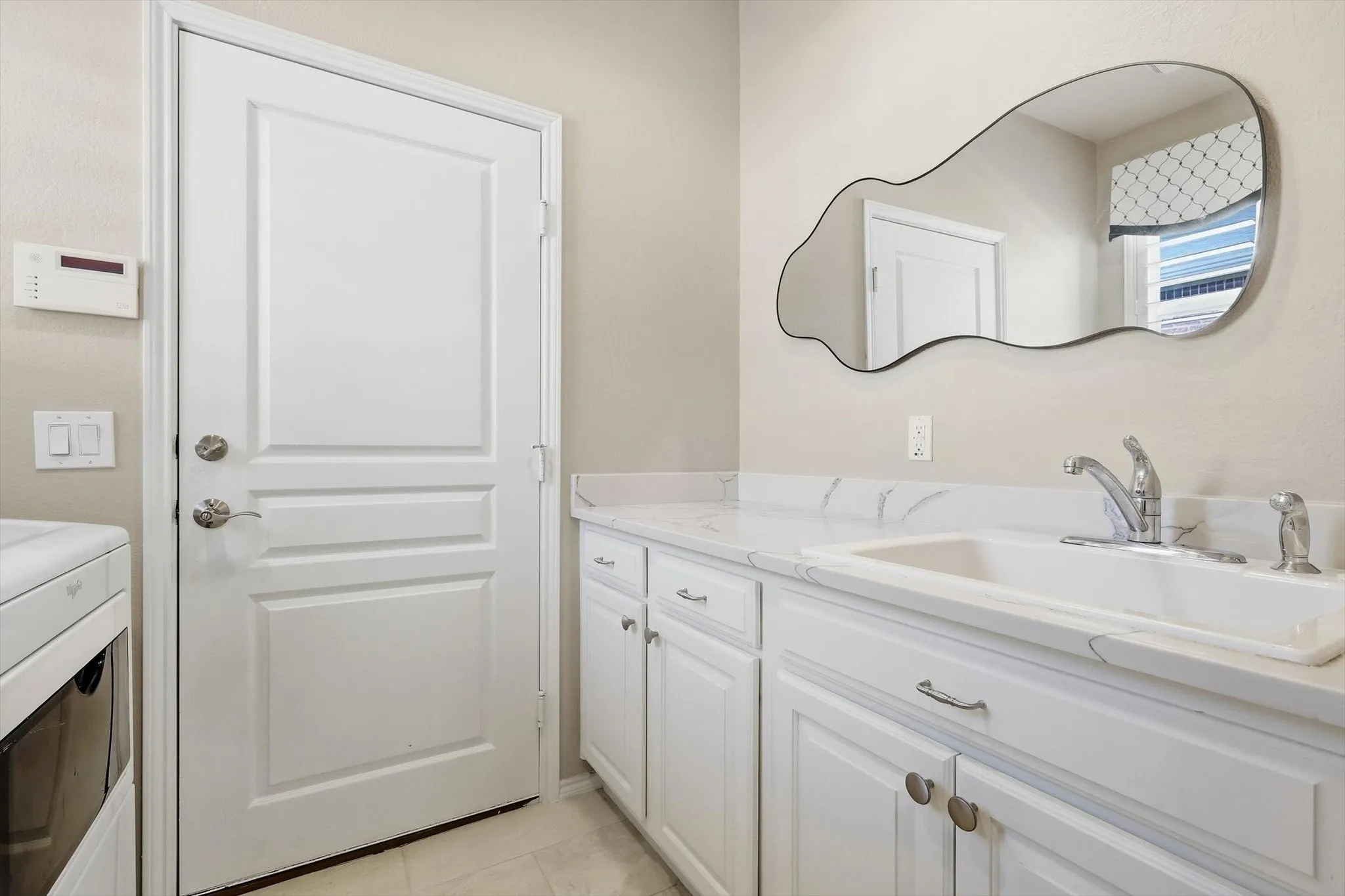 White shaker-style cabinetry with chrome hardware, an integrated sink, and a stone-finish countertop