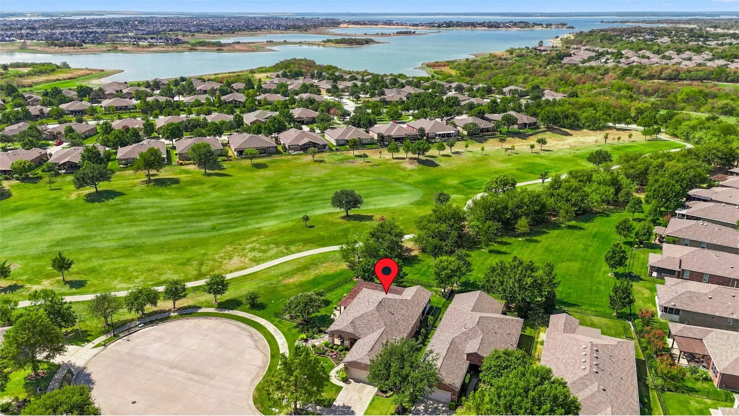 Cul-de-Sac location with lush green landscaping, a golf course, and a large body of water define the surrounding area