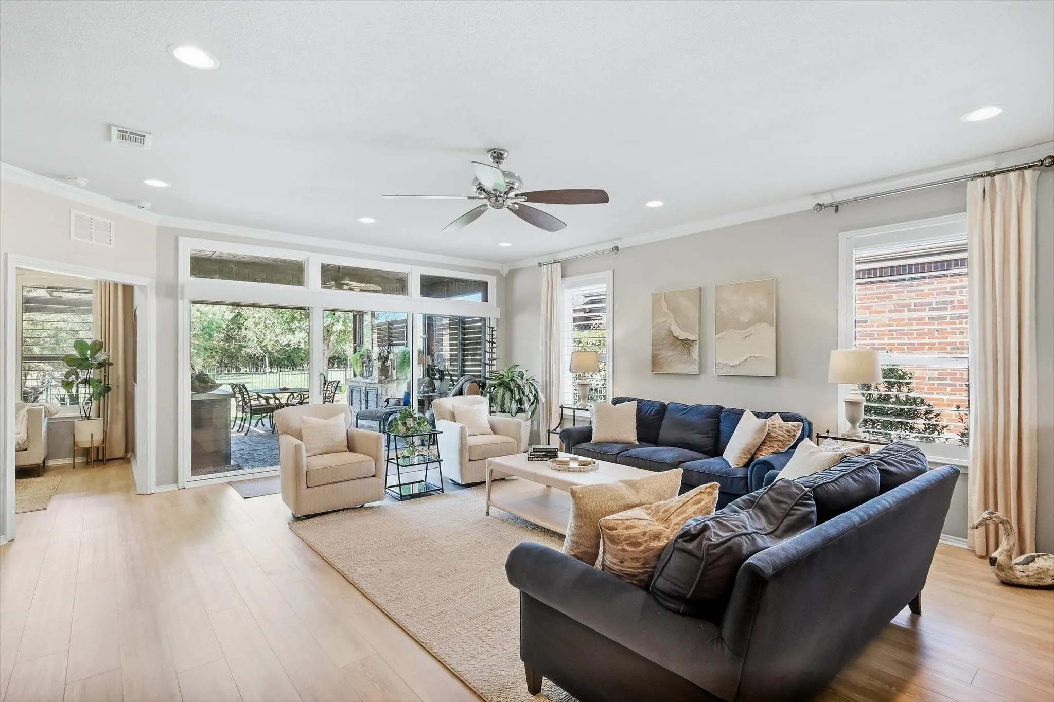 Spacious open-concept living area showcasing light wood-finish flooring, the study and large patio