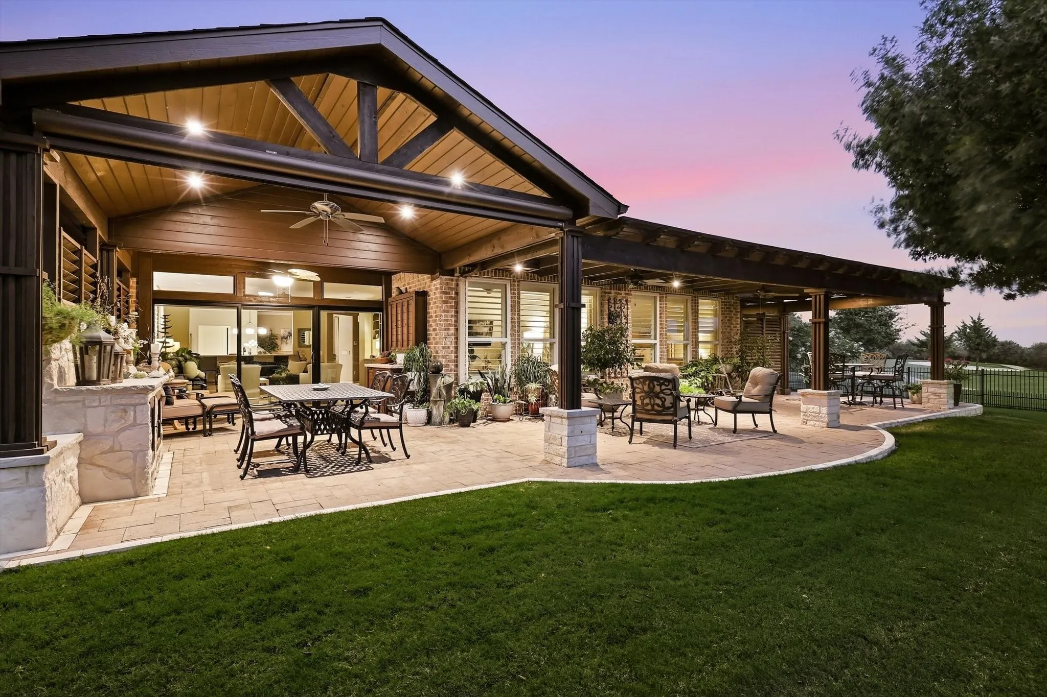 Expansive paver patio with a vaulted wooden ceiling, exposed wood beams, ceiling fans, and a pergola with wood beams